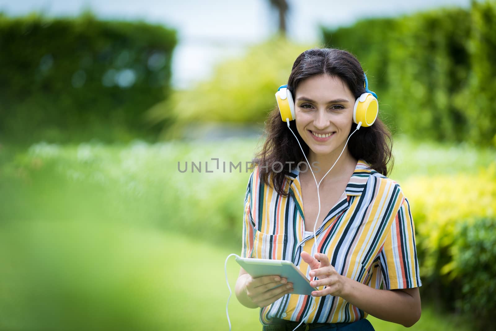 Portrait of a beautiful woman has listening to music with smiling and relax in the garden.