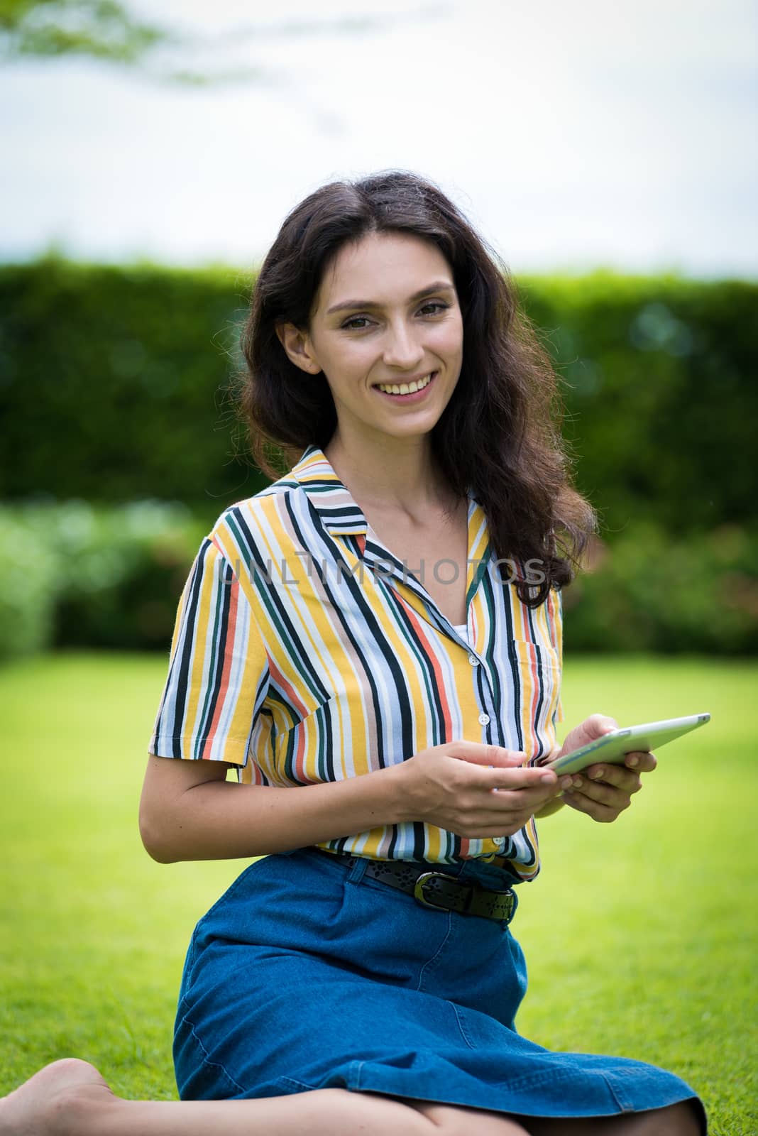 Portrait of a beautiful woman has playing tablet with smiling in the garden.