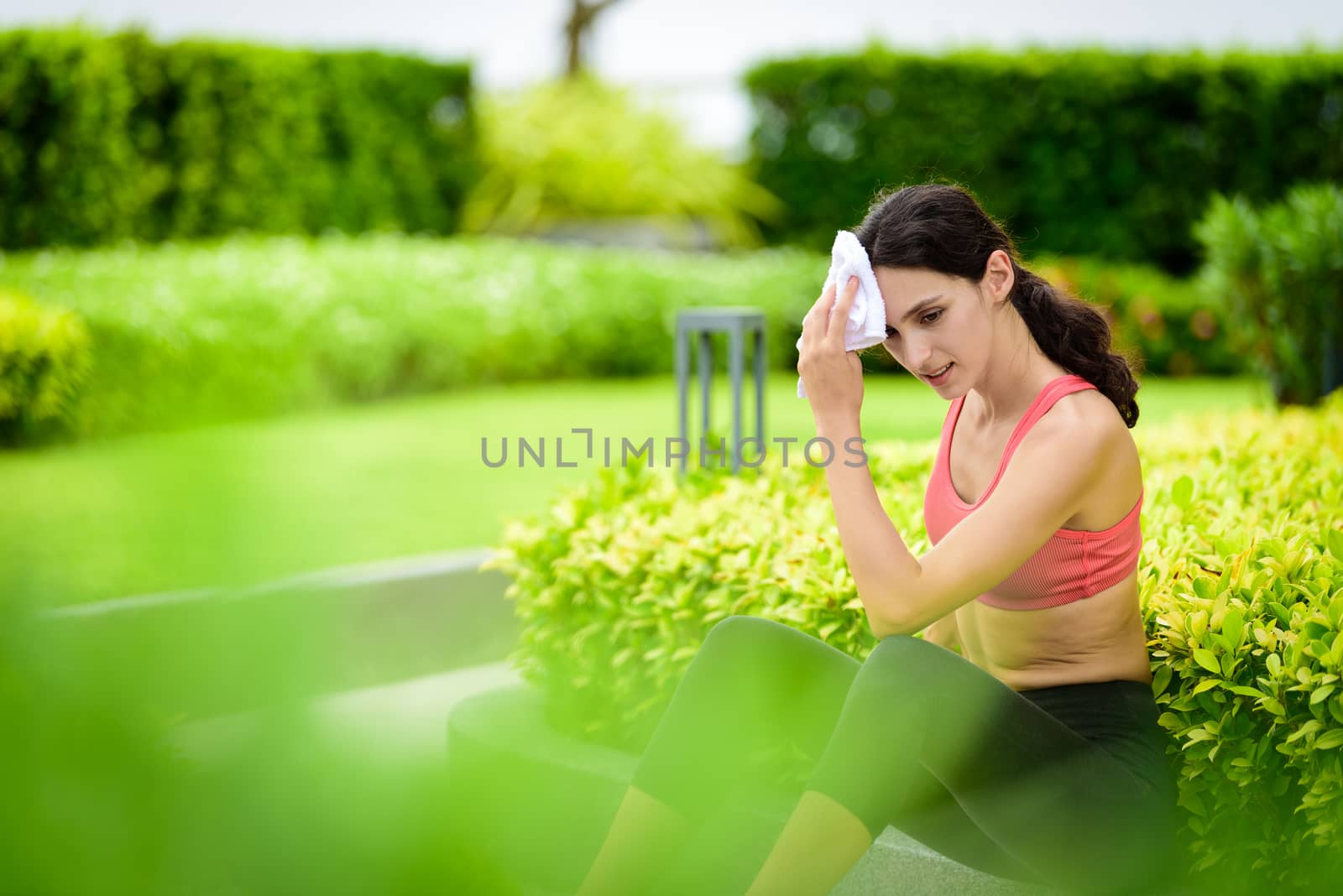 Beautiful woman runner has used a white towel wipe her face after running in the garden.