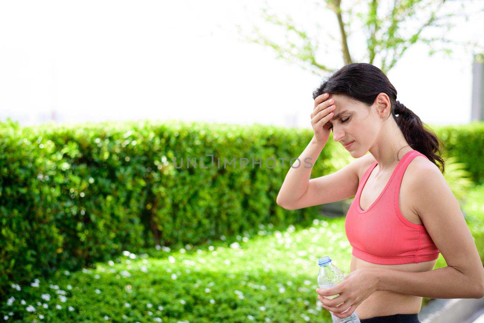 Beautiful woman runner has drinking water in the garden.