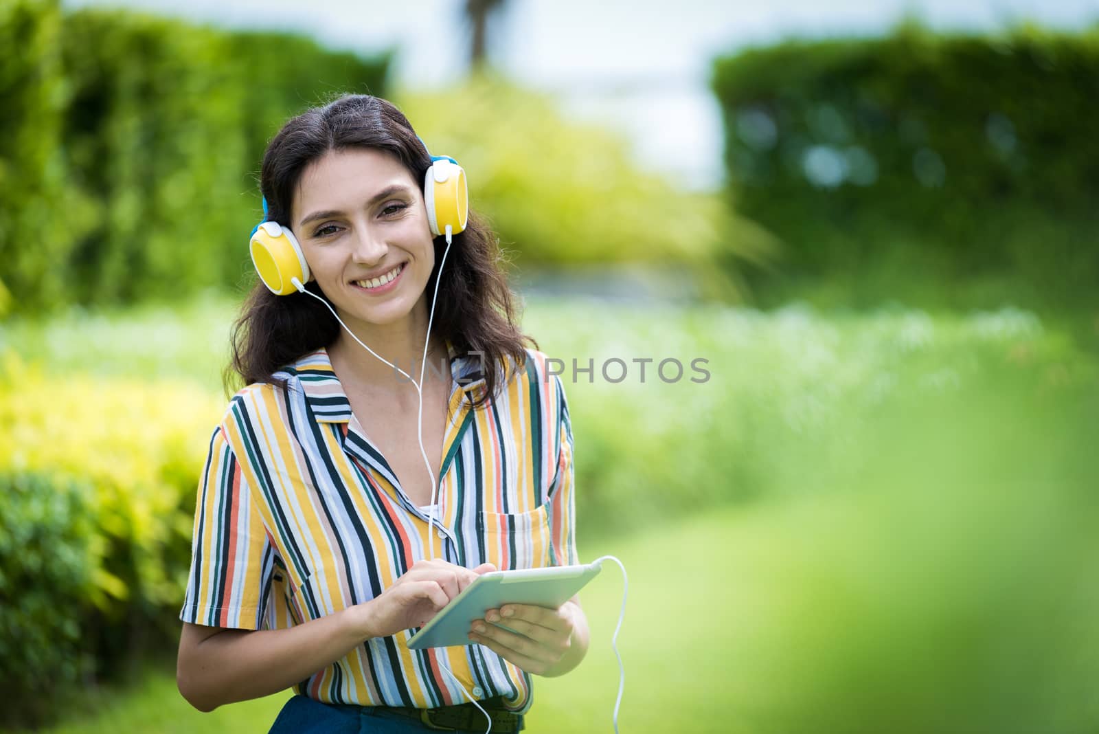 Portrait of a beautiful woman has listening to music with smiling and relax in the garden.