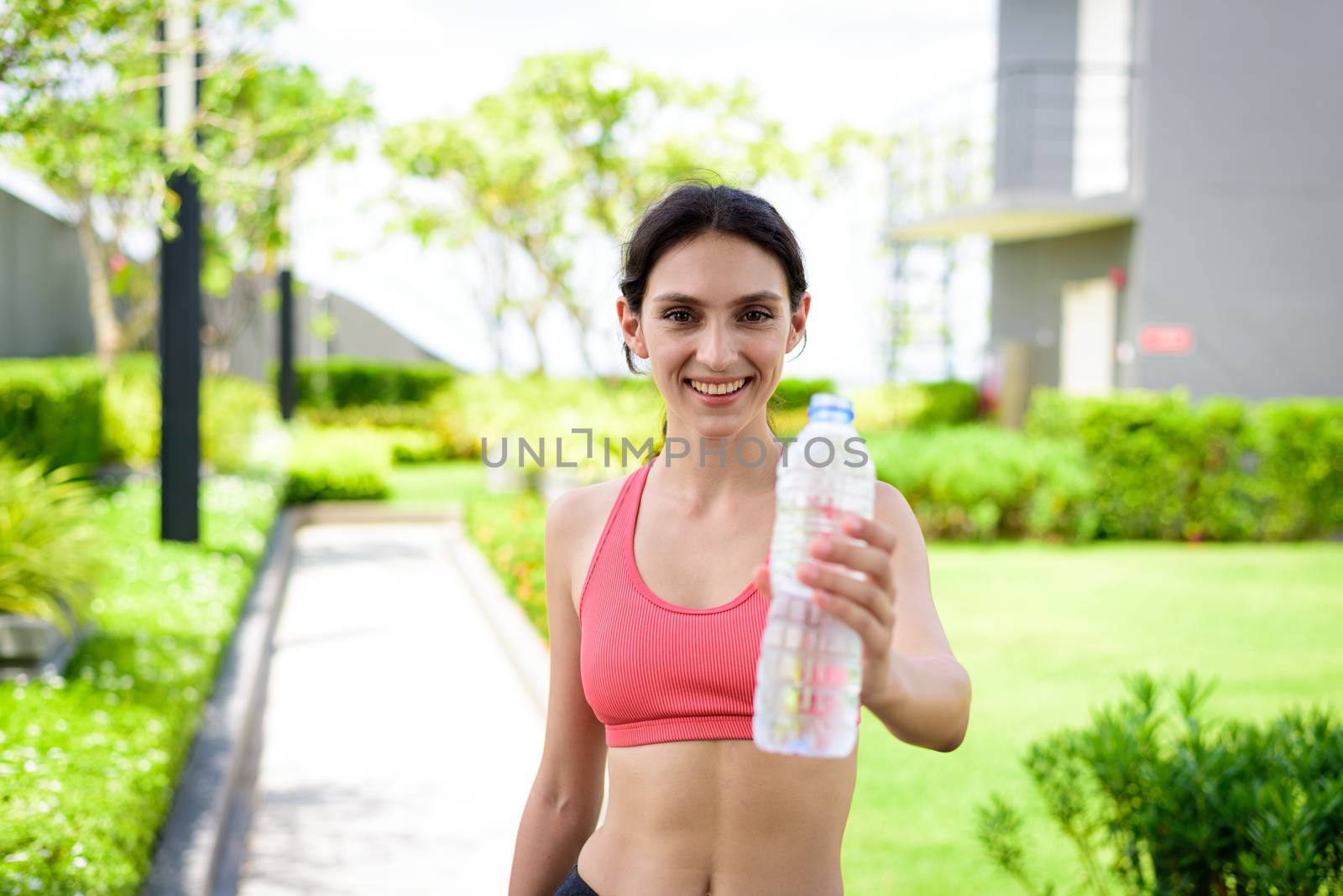 Beautiful woman runner has drinking water in the garden.