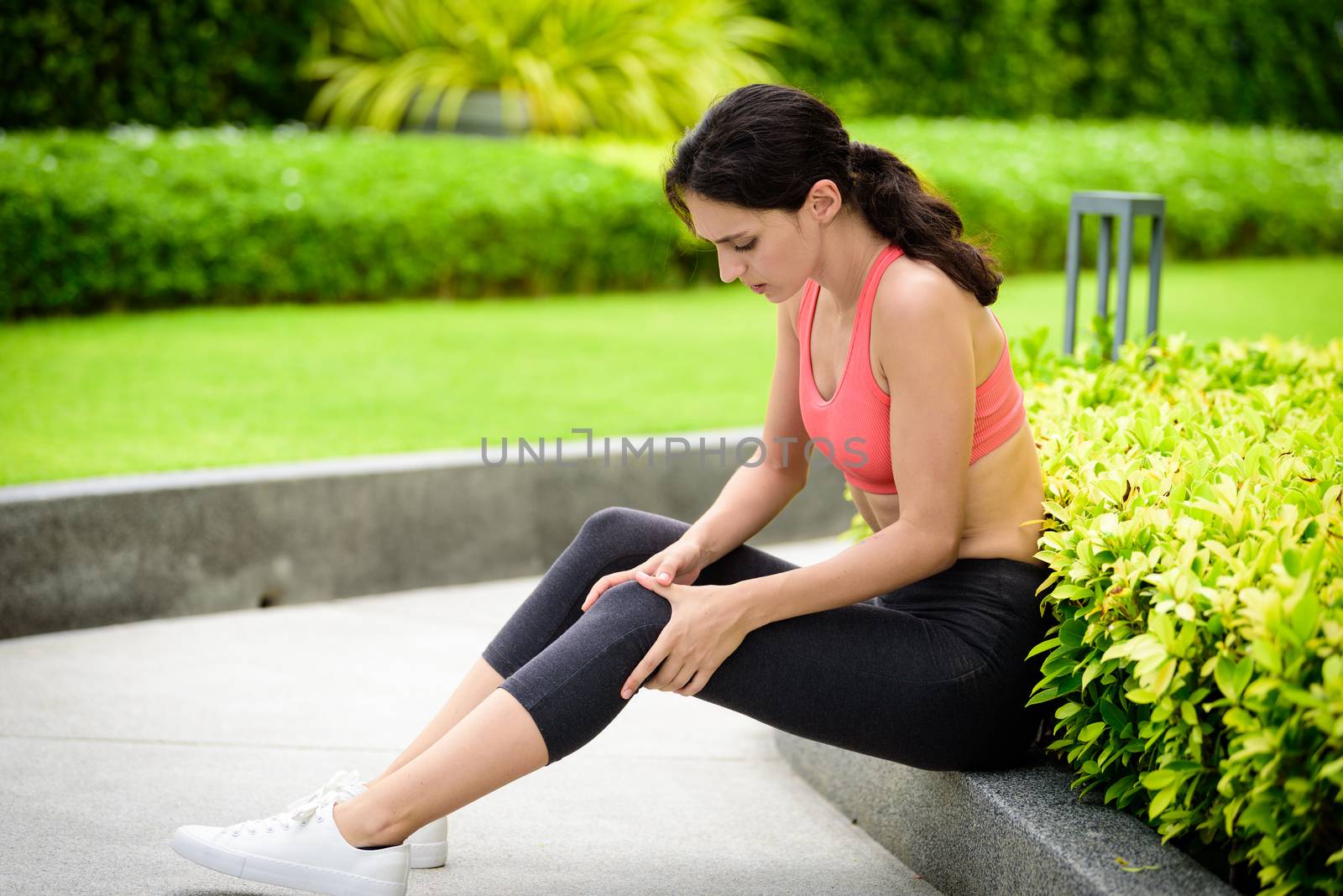 Beautiful woman runner has feeling painful leg in the garden.