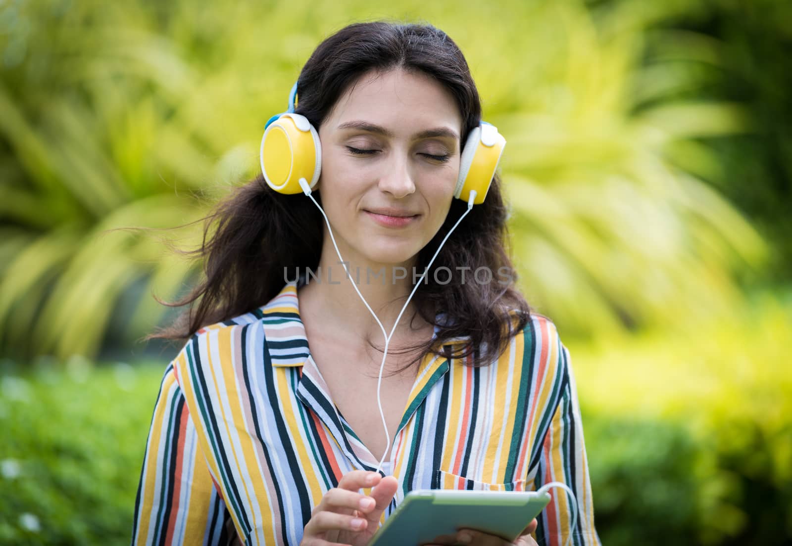 Portrait of a beautiful woman has listening to music with smiling and relax in the garden.