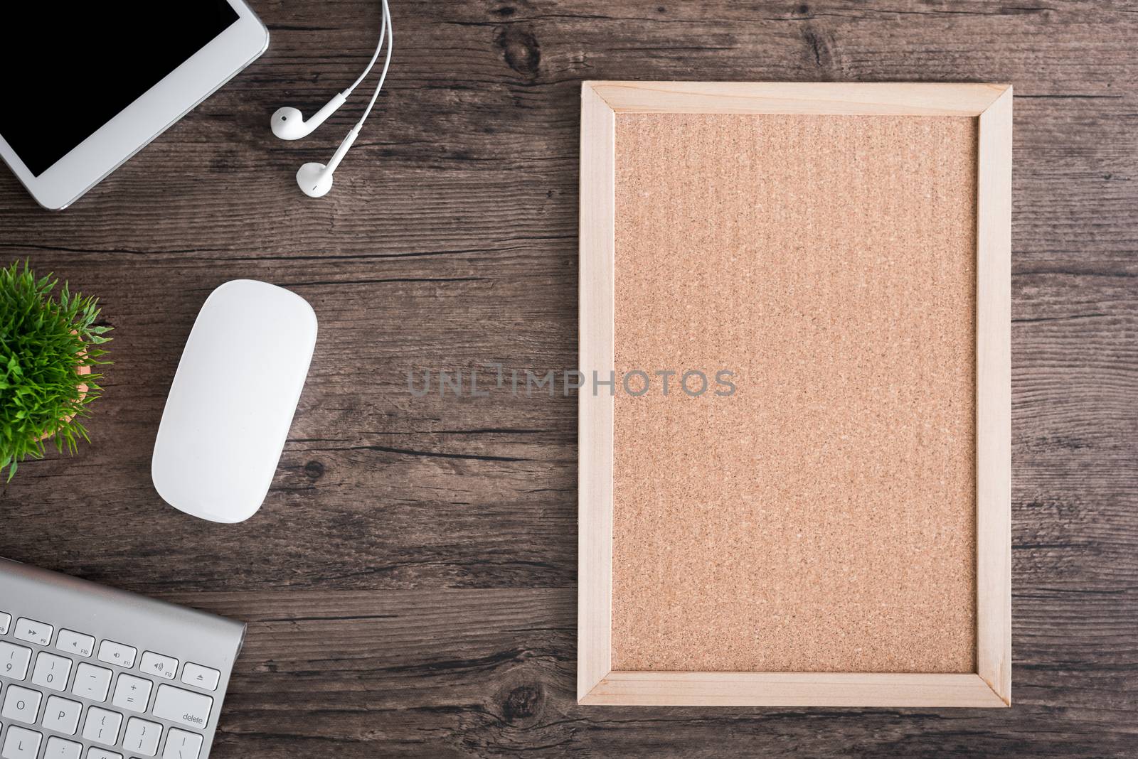 The office desk flat lay view with keyboard, mouse, tree, office pin board and earphone on wood texture background.