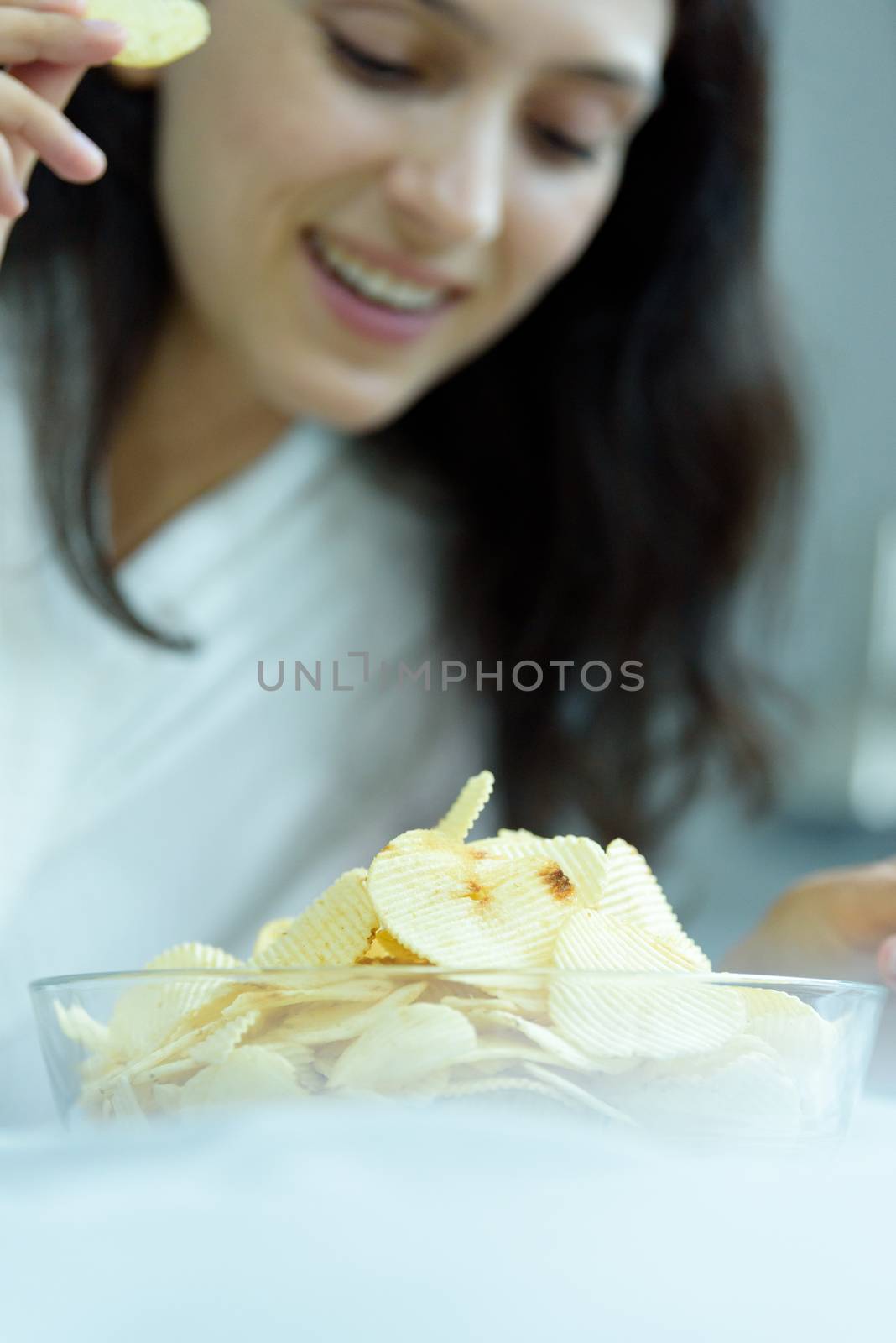 A beautiful woman eating snack potato and playing laptop with lying down on the bed and happiness at a condominium in the morning.