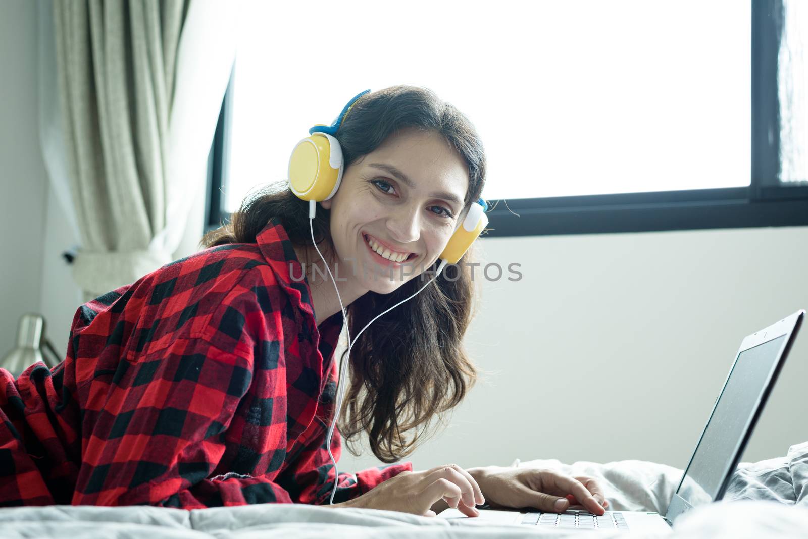 Beautiful woman working and listening to music on a laptop with  by animagesdesign