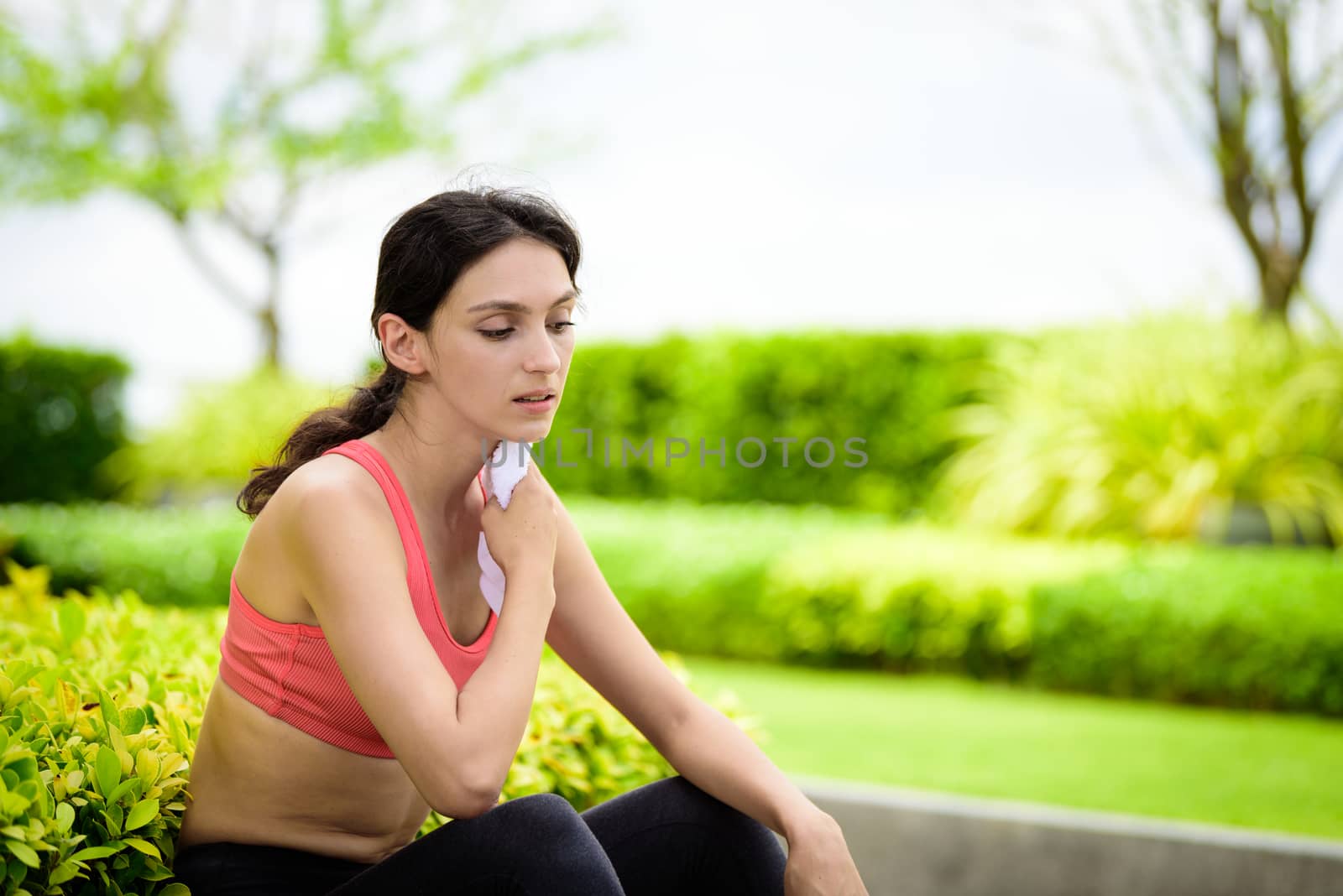 Beautiful woman runner has used a white towel wipe her face after running in the garden.