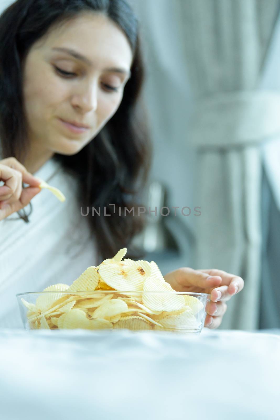 A beautiful woman eating snack potato and playing laptop with lying down on the bed and happiness at a condominium in the morning.