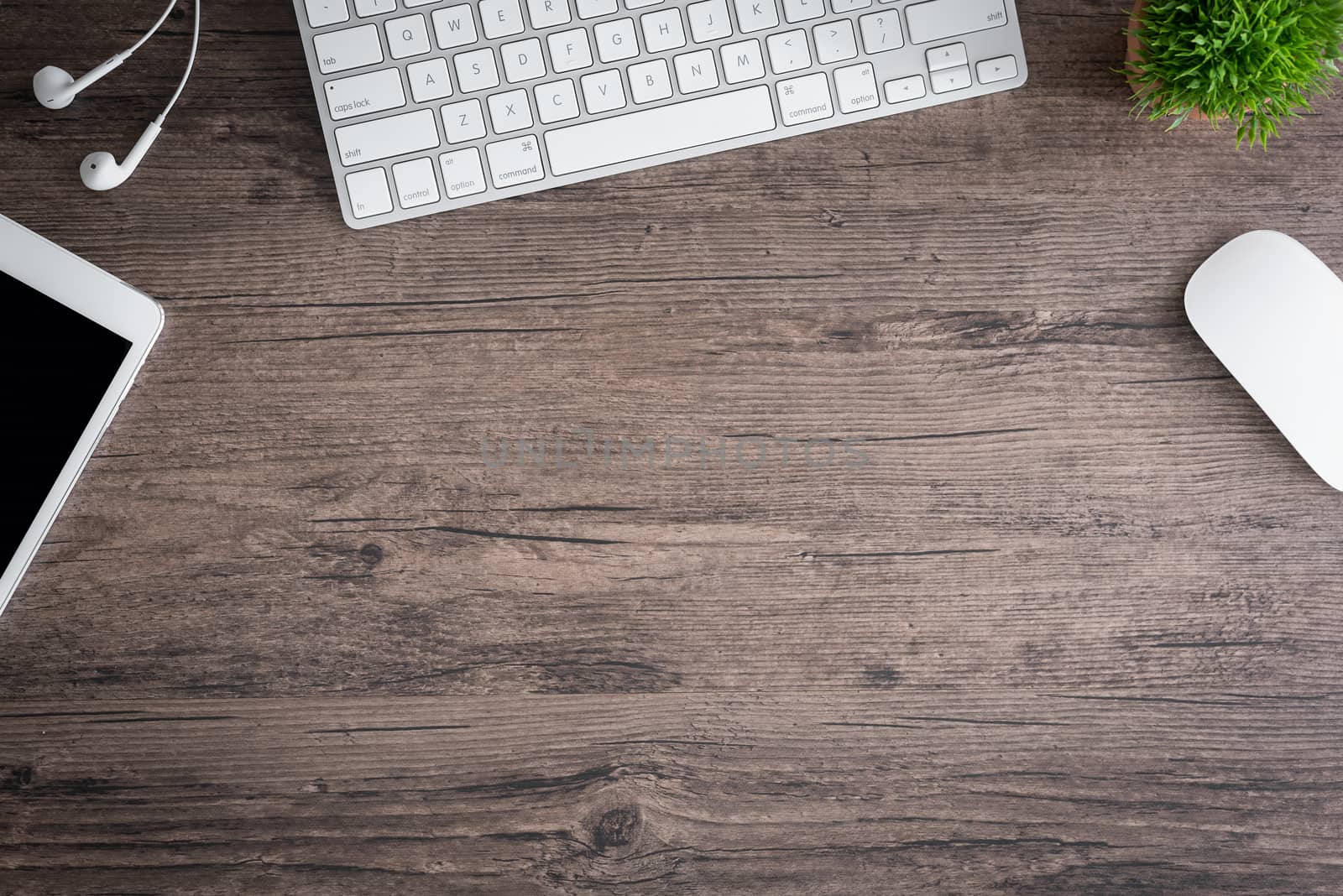 The office desk flat lay view with keyboard, mouse, tree and earphone on wood texture background.