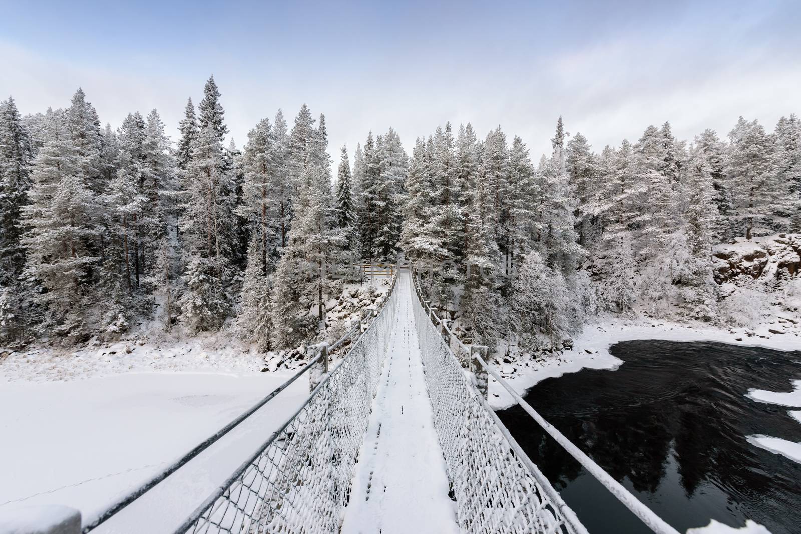 The bridge has covered with heavy snow and sky in winter season at Oulanka National Park, Finland.