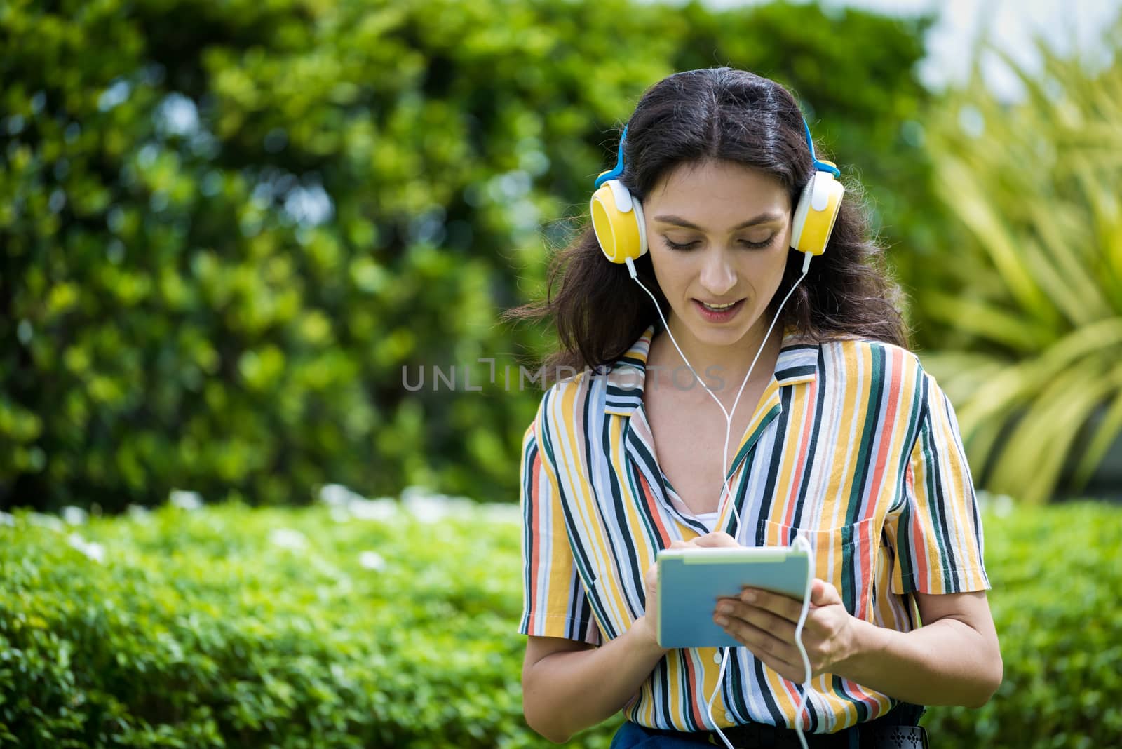Portrait of a beautiful woman has listening to music with smiling and relax in the garden.