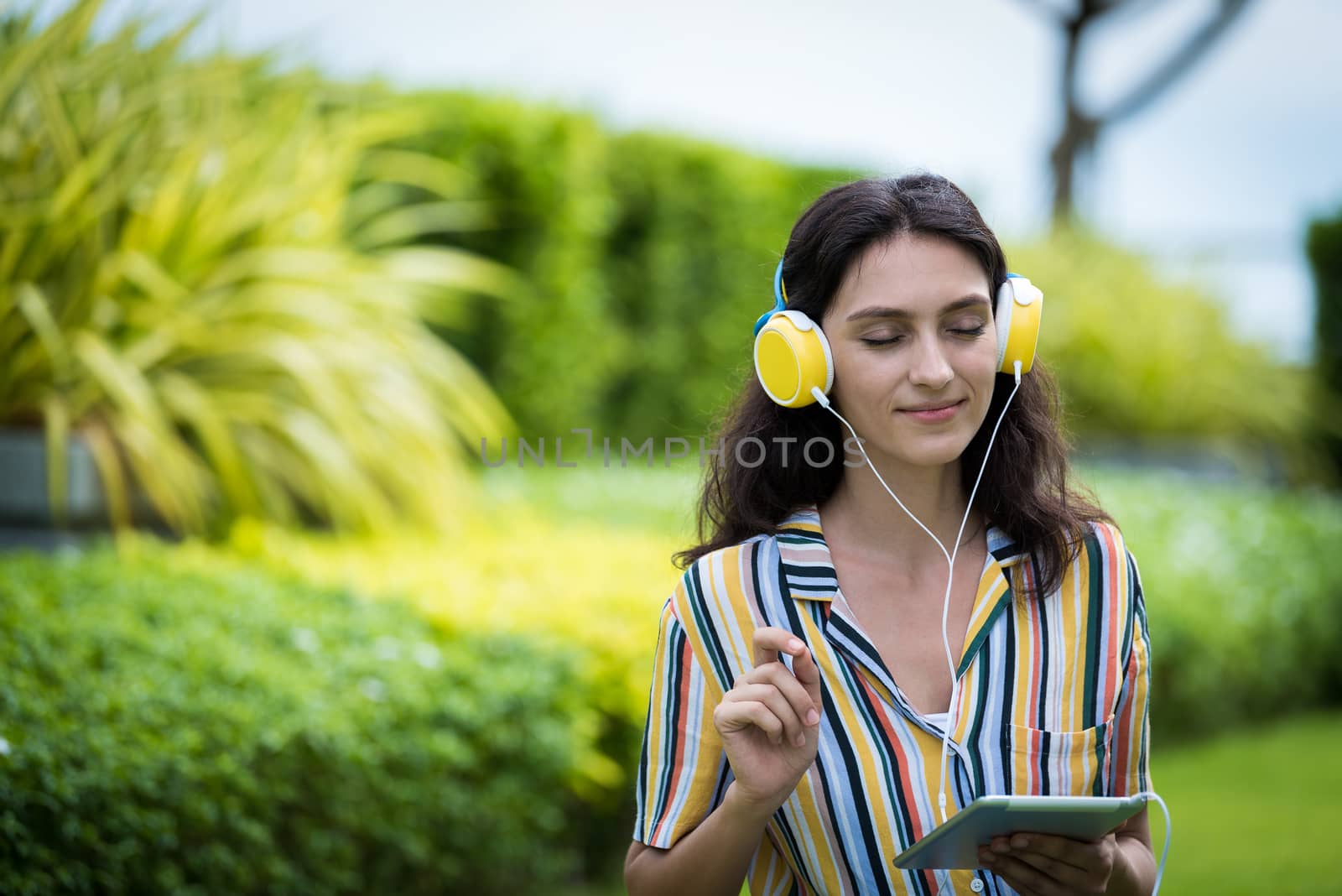 Portrait of a beautiful woman has listening to music with smiling and relax in the garden.