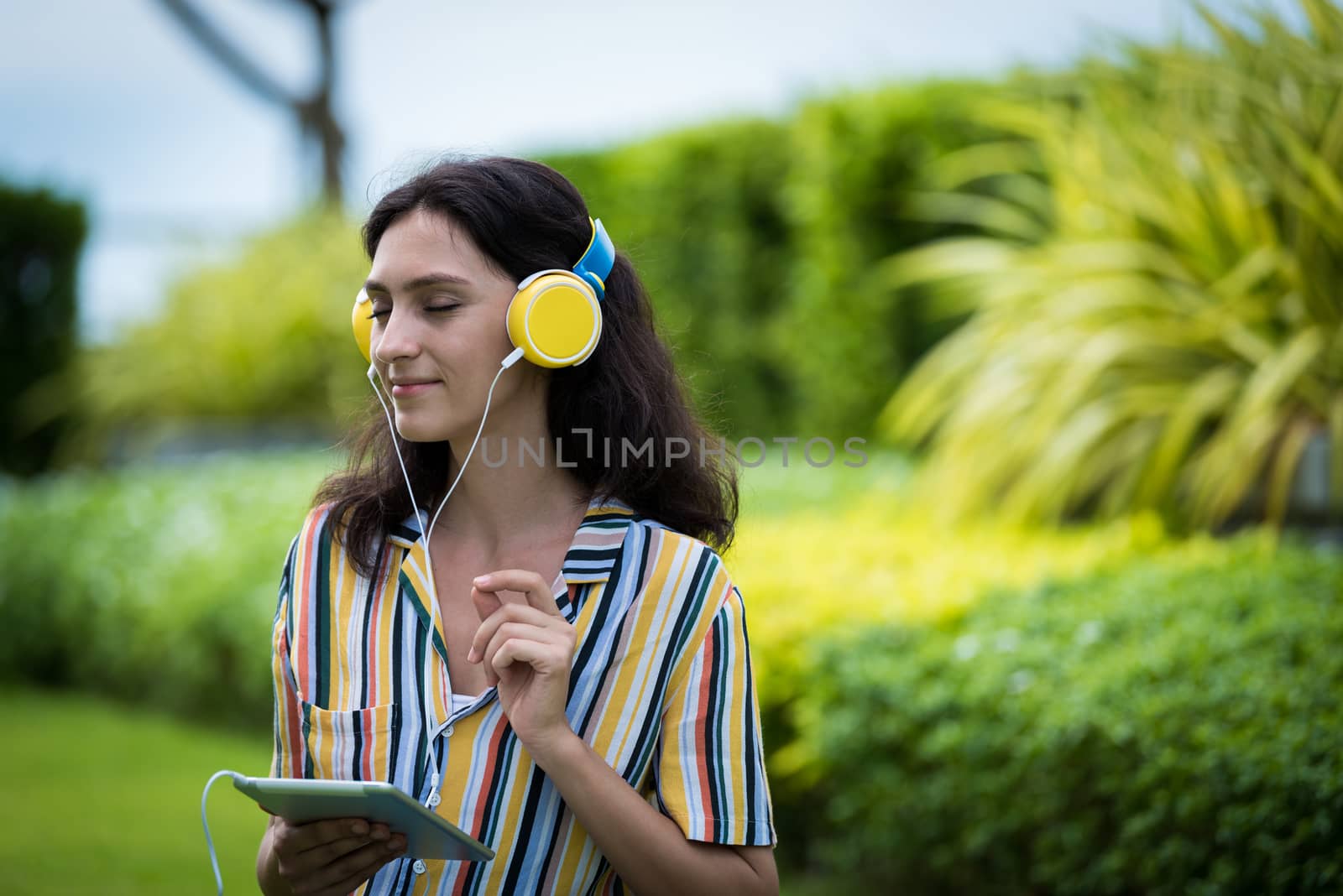 Portrait of a beautiful woman has listening to music with smiling and relax in the garden.