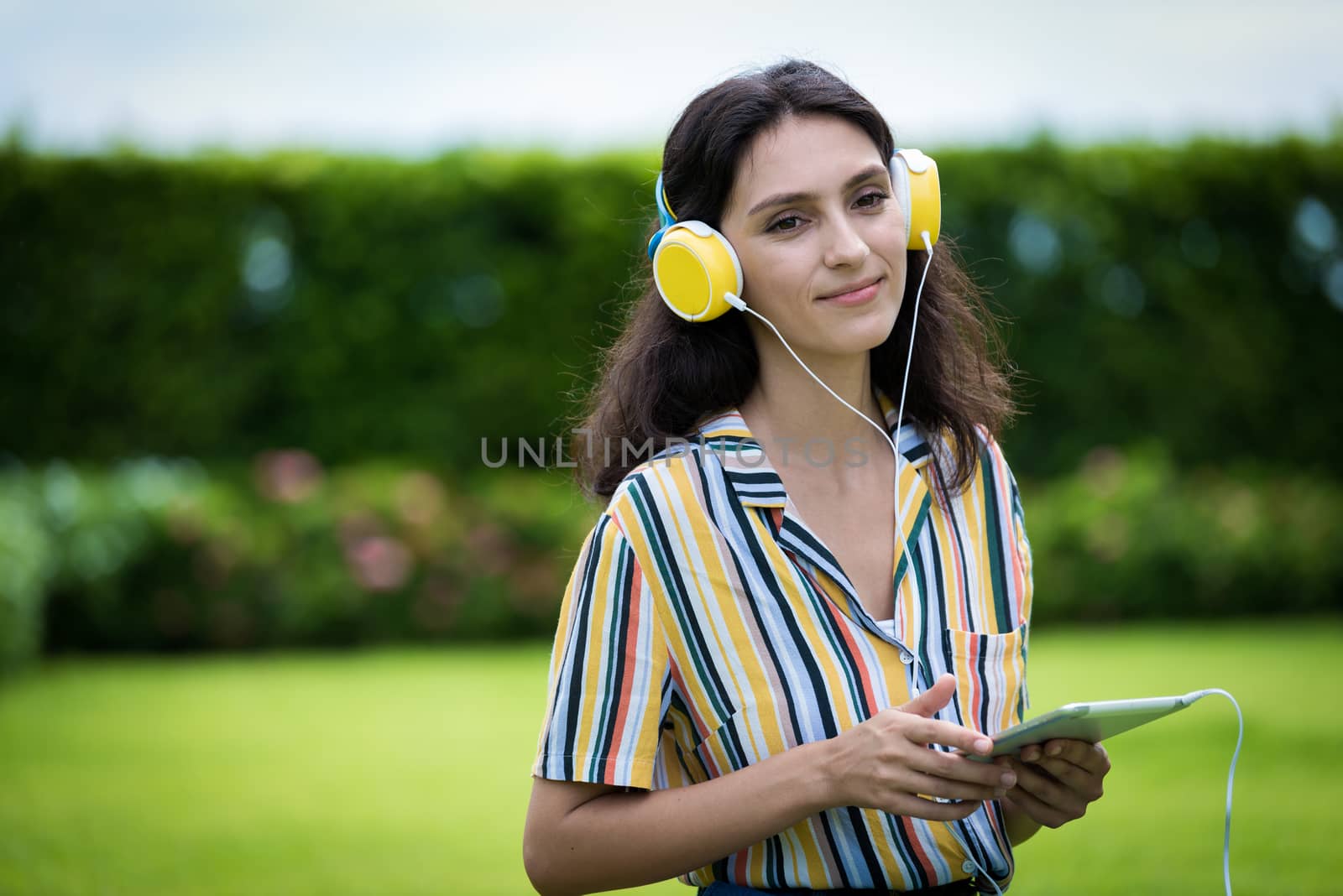 Portrait of a beautiful woman has listening to music with smiling and relax in the garden.