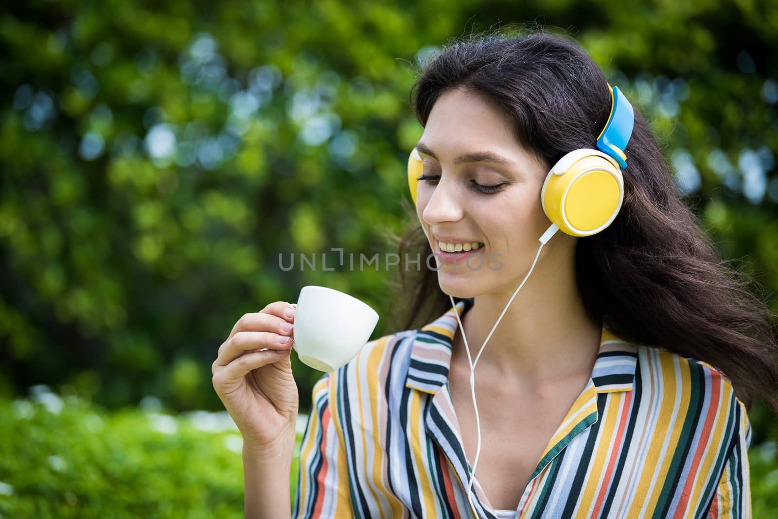 Portrait of a beautiful woman has drunk a coffee and listening to music with smiling and relax in the garden.