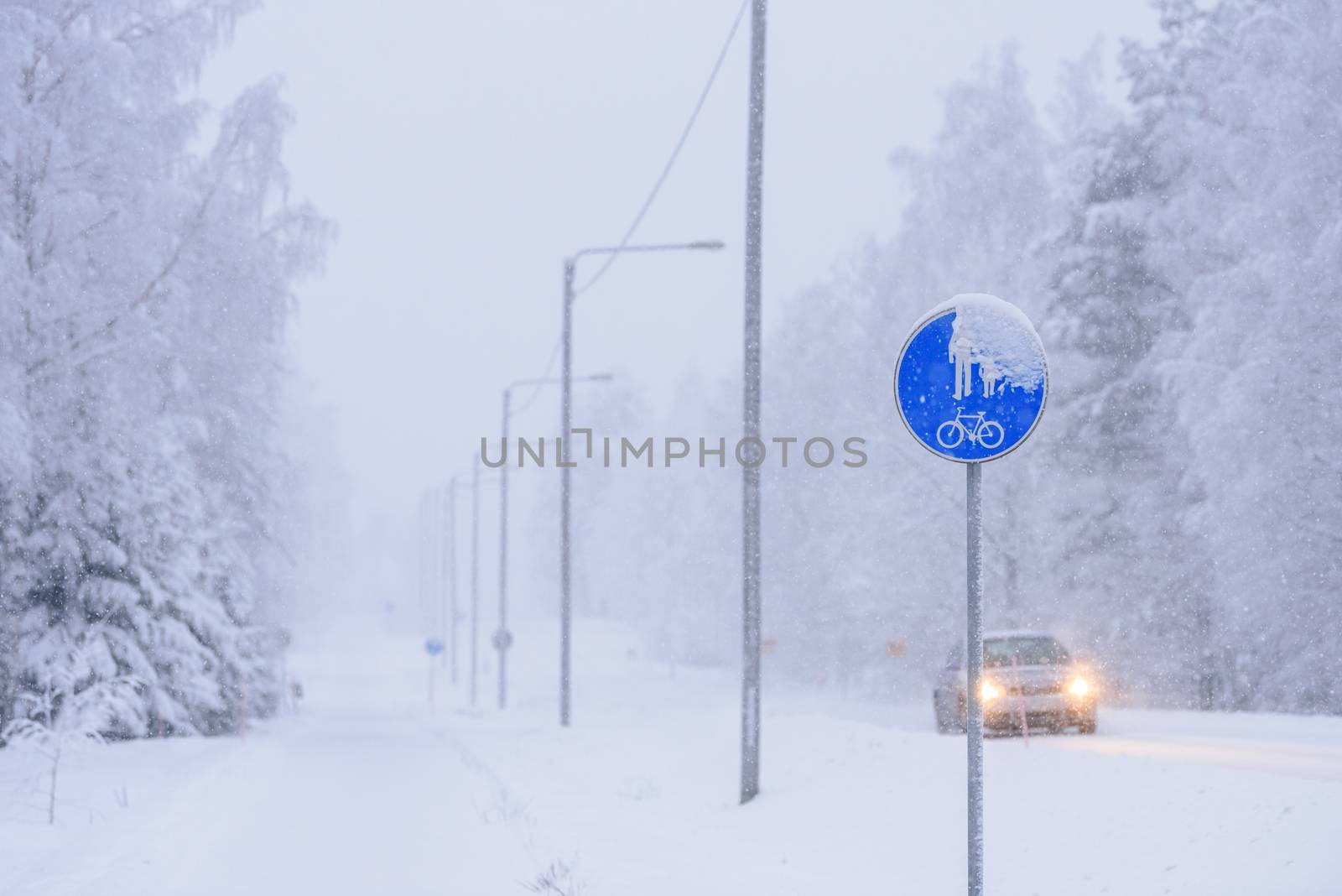 The sign of a bike path and a pedestrian on the road in winter at Tuupovaara, Finland