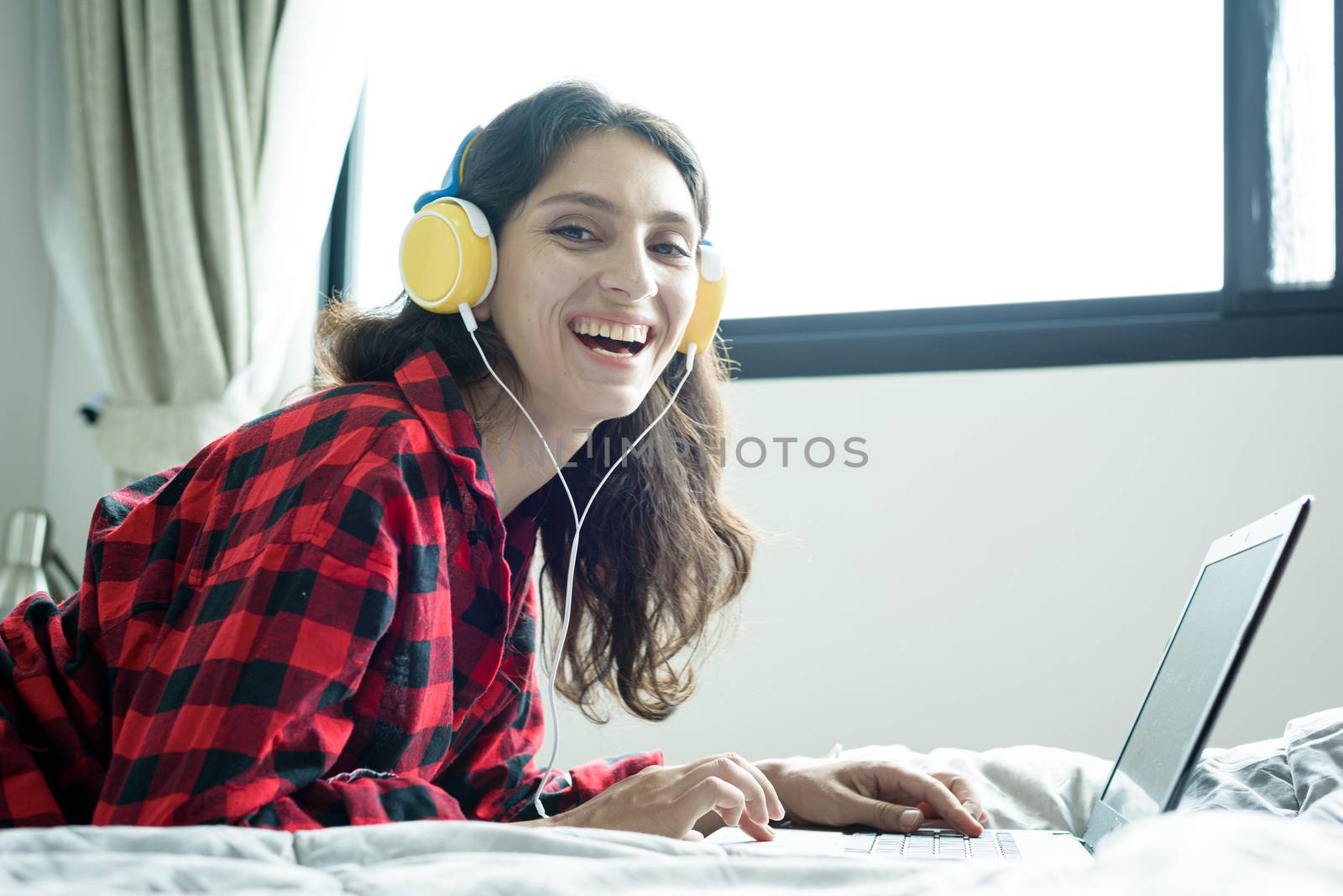 Beautiful woman working and listening to music on a laptop with  by animagesdesign