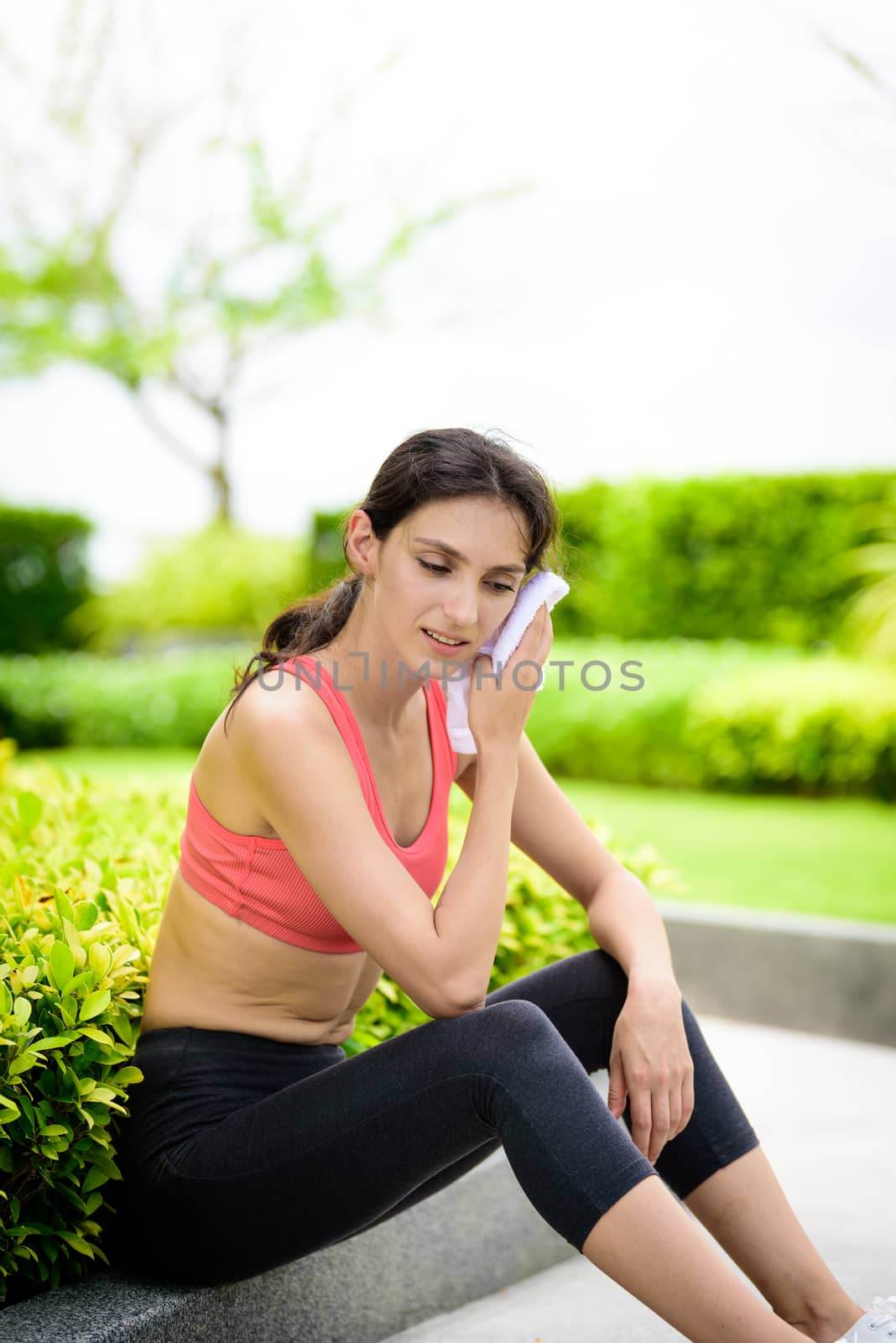 Beautiful woman runner has used a white towel wipe her face after running in the garden.