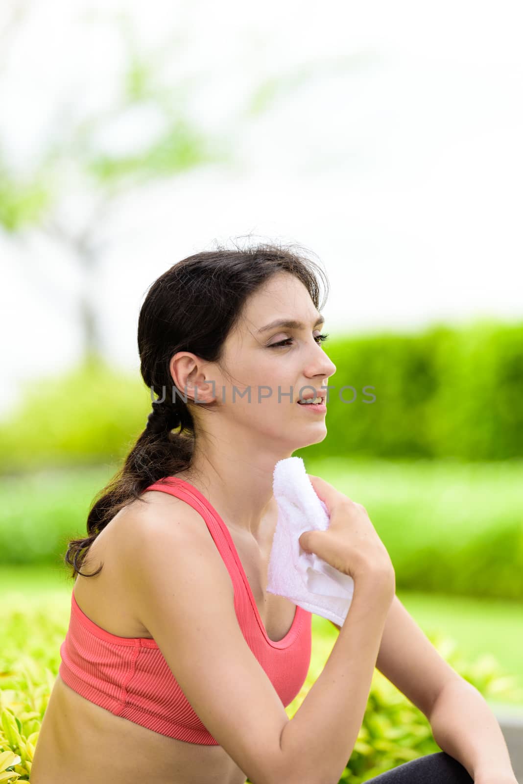 Beautiful woman runner has used a white towel wipe her face afte by animagesdesign