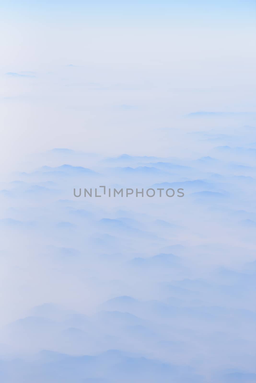 The mountains has covered by cloudy in sunrise time, view from window on the plane.