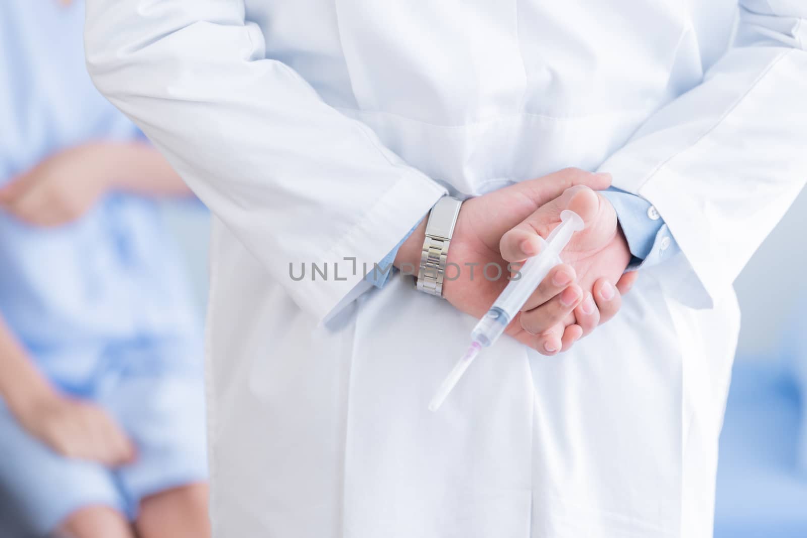 The doctor holding the syringe behind his back and waiting for checking the patient.