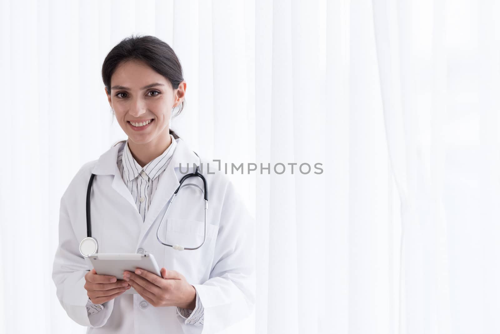 A doctor woman has to work with touching the tablet at the hospital with smiling and happiness.