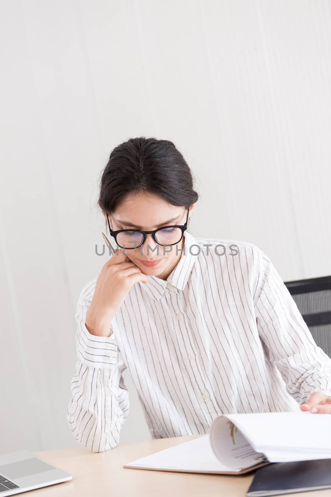 A businesswoman wearing glasses working with smiling and happiness at the office.