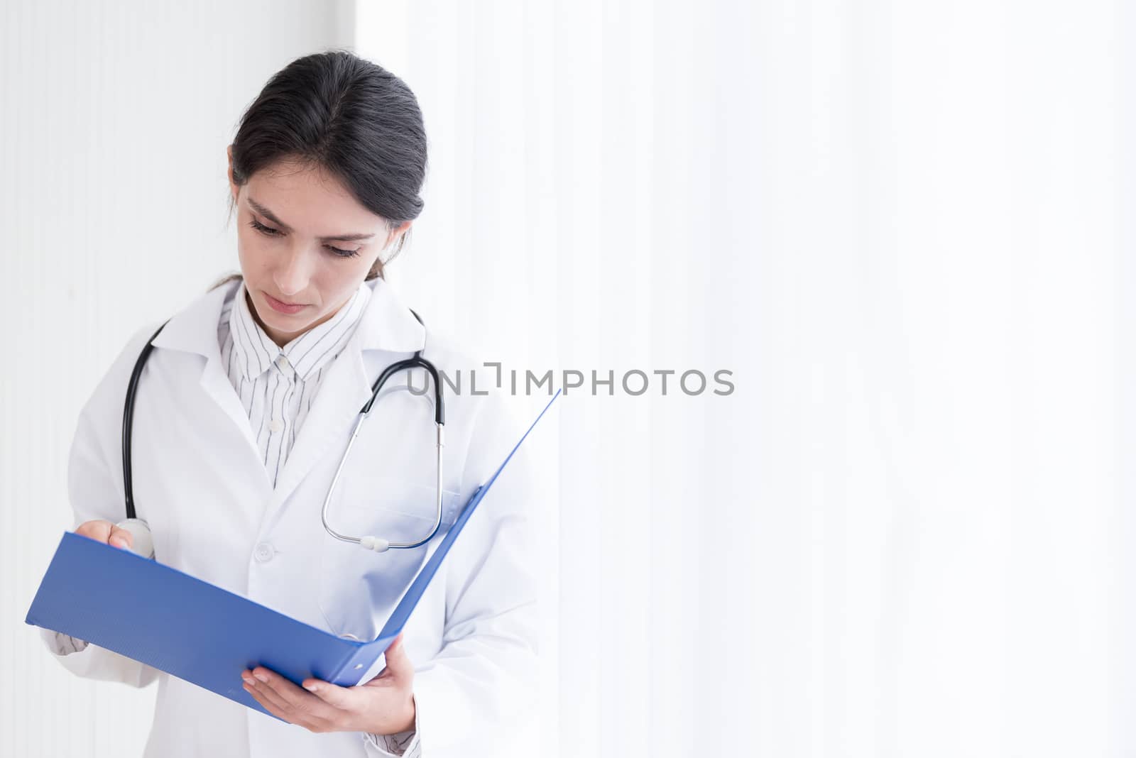 A doctor woman has to work with reading the report at the hospital.