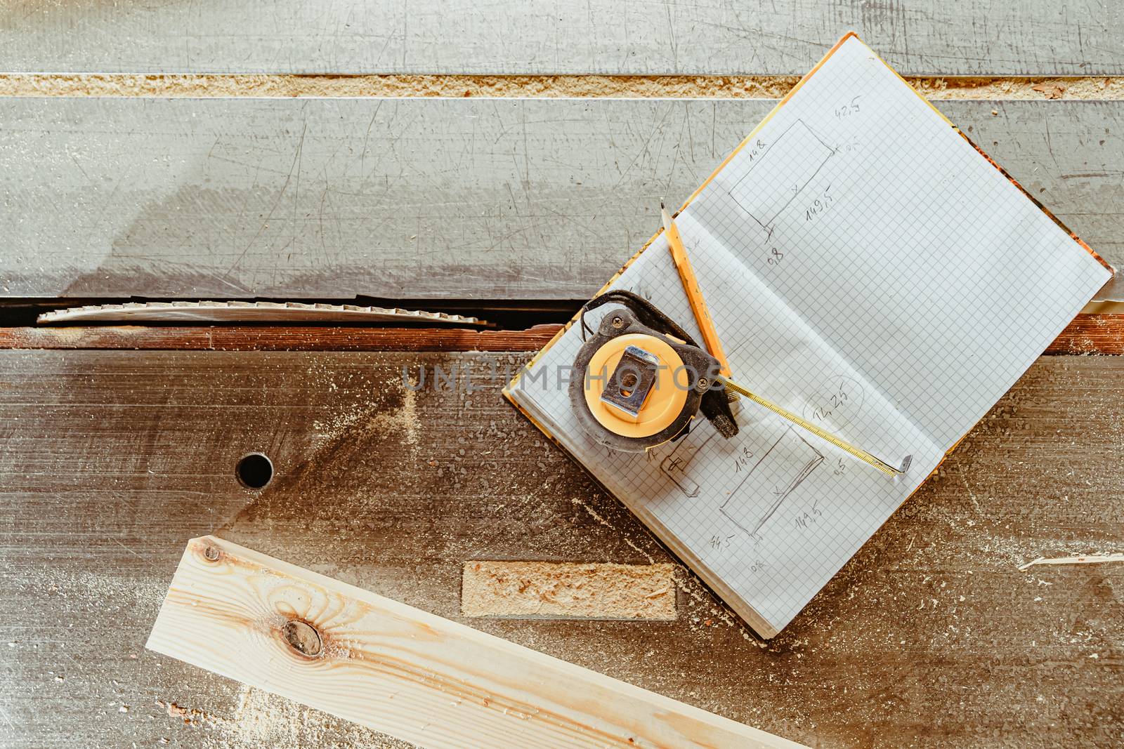 tools for planning a wooden product: meter, pencil and workbook on a workbench in a joinery.