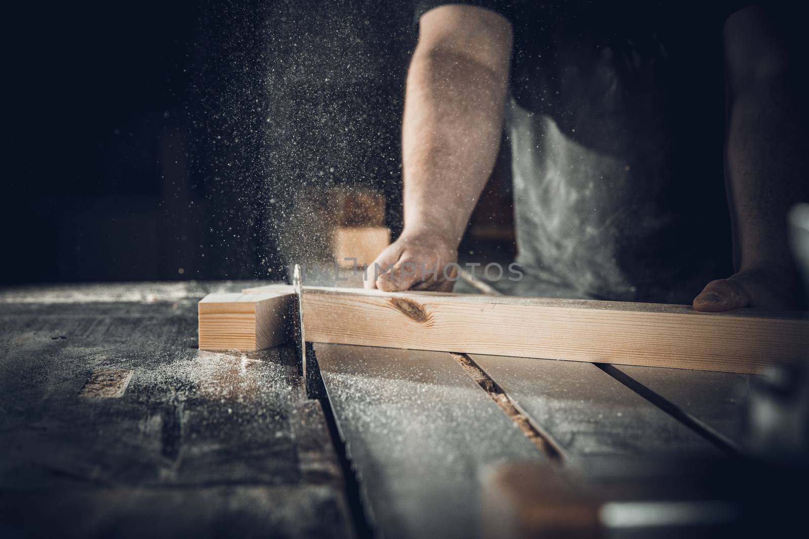 carpenter cuts wooden plank on circular saw.