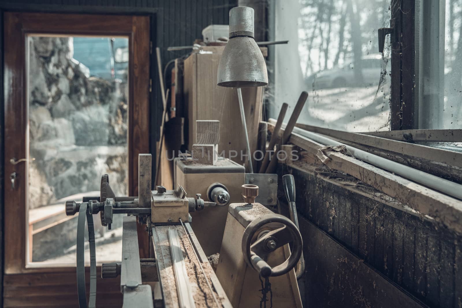 old lathe in an old carpenter's standing by a window covered with dust and spiderwebs.