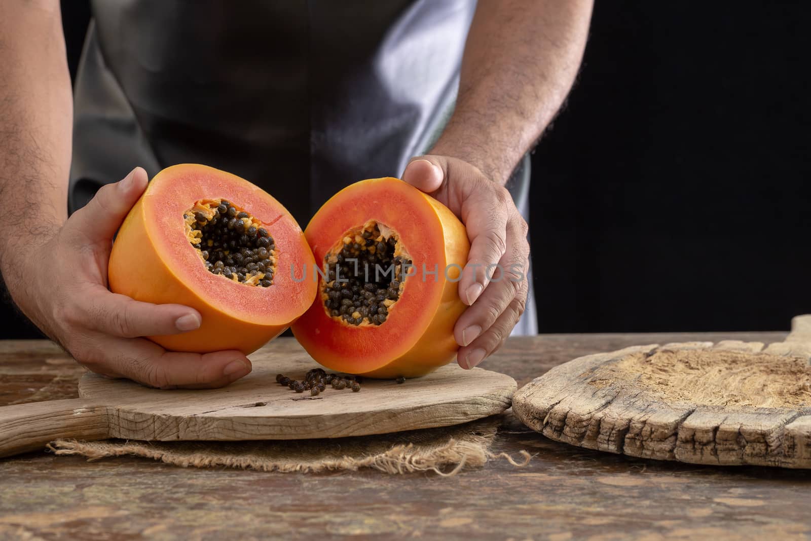 Ripe papaya fruit cut into pieces on wooden background by kaiskynet