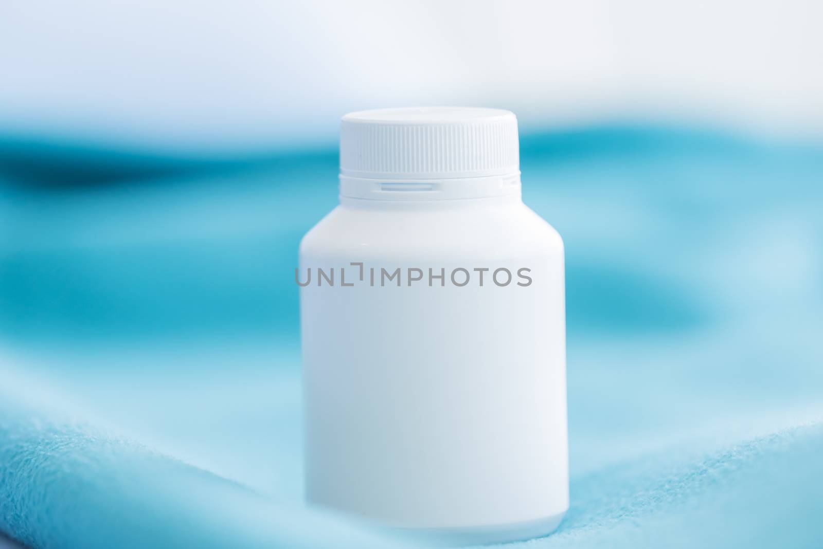 A white medicine bottle on the green bed sheet. by animagesdesign