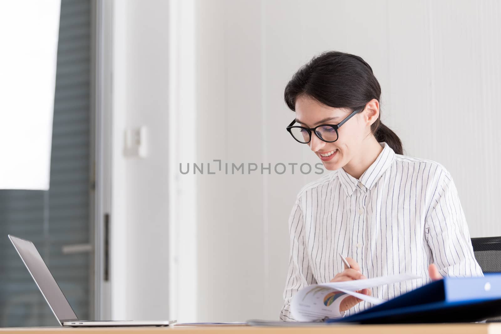 A businesswoman wearing glasses working with smiling and happiness at the office.