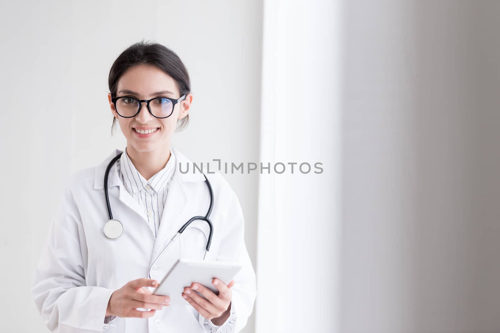 A doctor woman has to work with touching the tablet at the hospital with smiling and happiness.