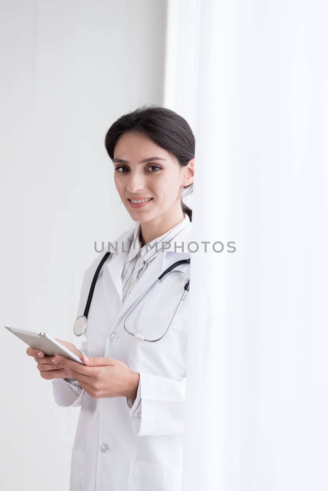 A doctor woman has to work with touching the tablet at the hospital with smiling and happiness.