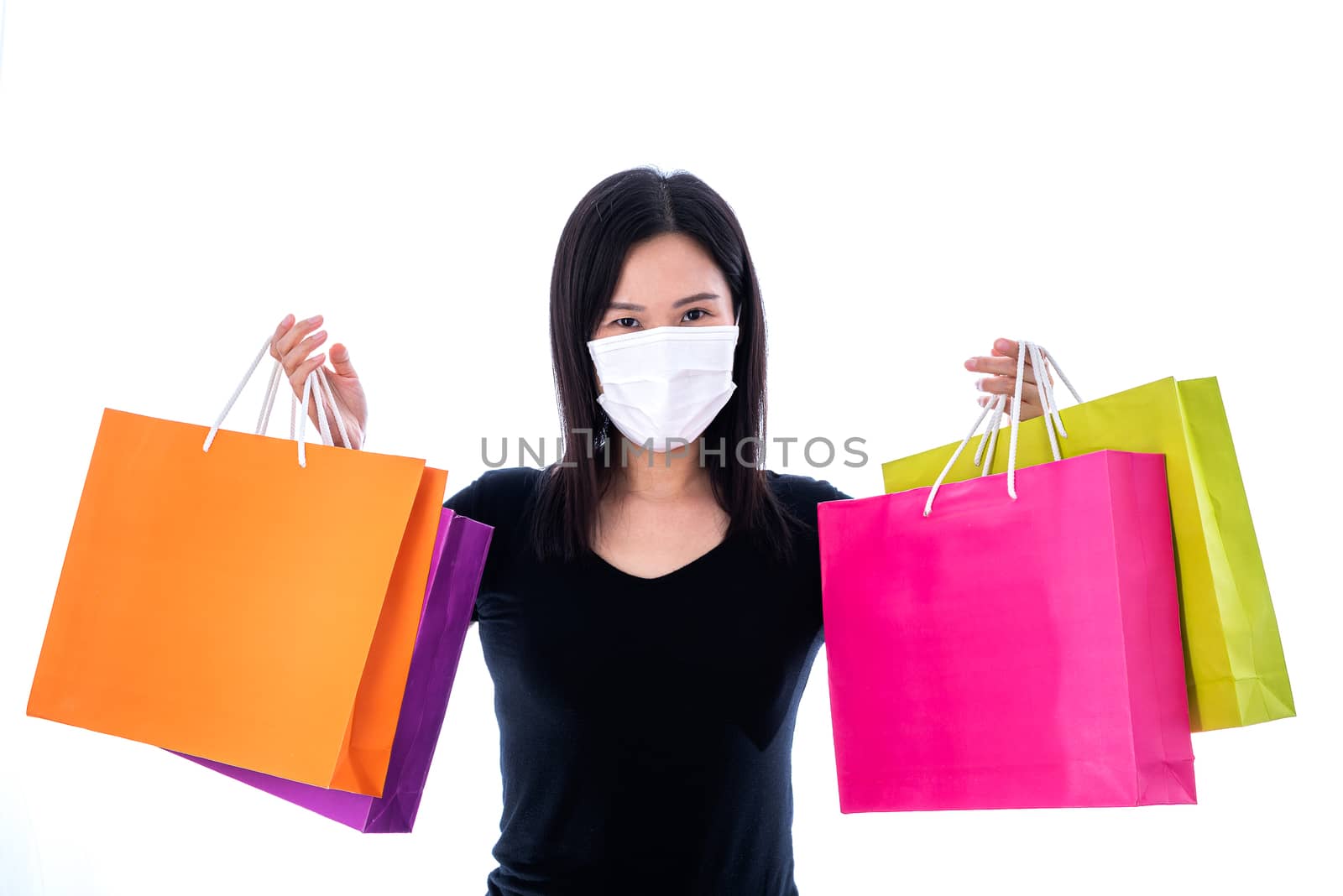 An Asian woman shopping with colorful paper bag and wearing a white mask to protect COVID-19.