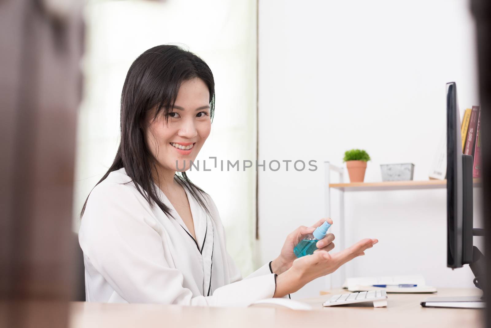 A beautiful Asian businesswoman cleaning hands by cleaner gel to by animagesdesign