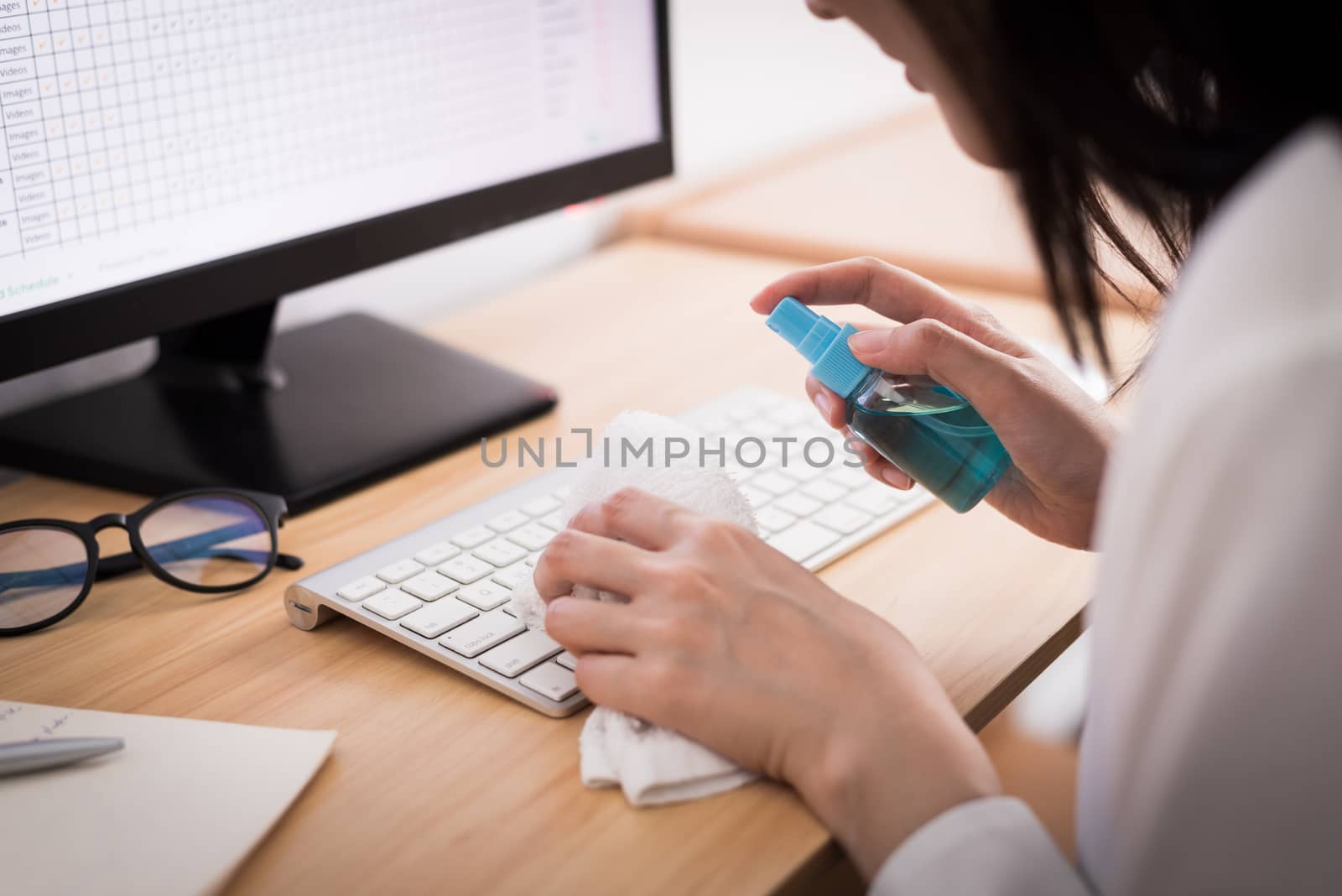 A beautiful Asian businesswoman cleaning a keyboard by cleaner gel and white cloth to protect COVID-19 before start working from home with safety and happiness.