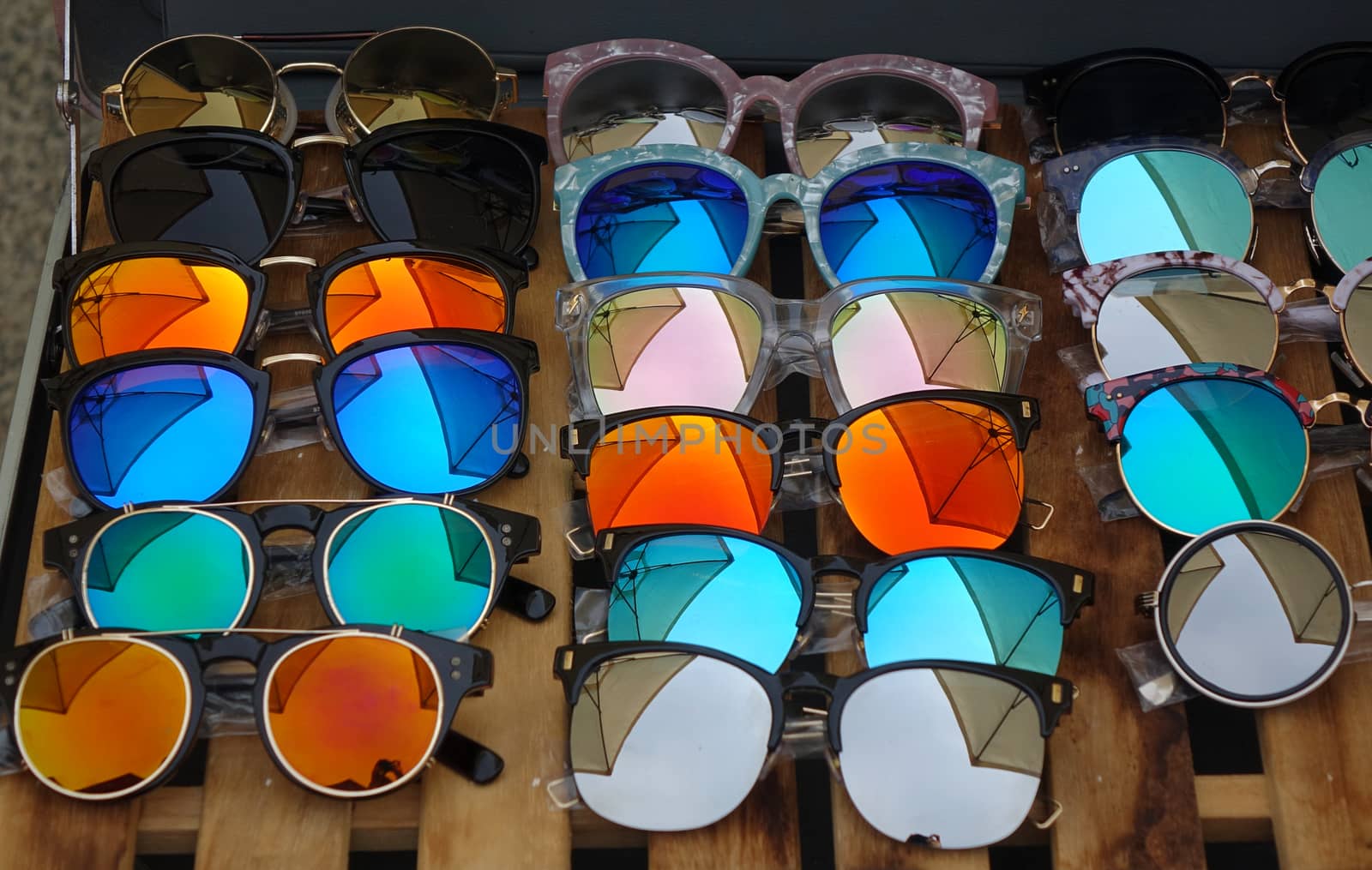 An outdoor vendor at a tourist market sells reflecting sunglasses.