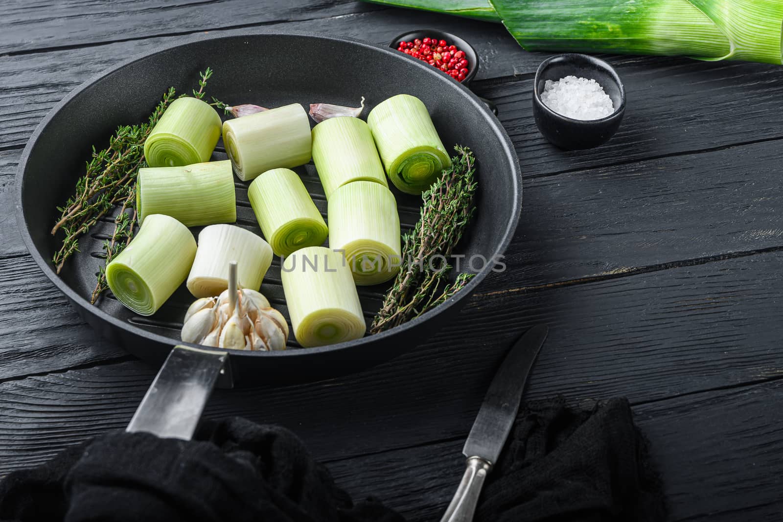 Raw braised Leek sultan on grill pan uncooked with herbs ingredients , on black wooden table side view with space for text