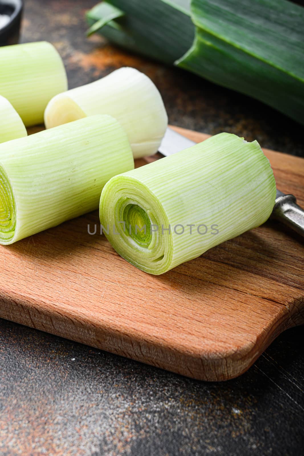 Raw chopped leek for cooking Braised Leeks with herbs ingredients , on rustic metall background dark, side view. by Ilianesolenyi