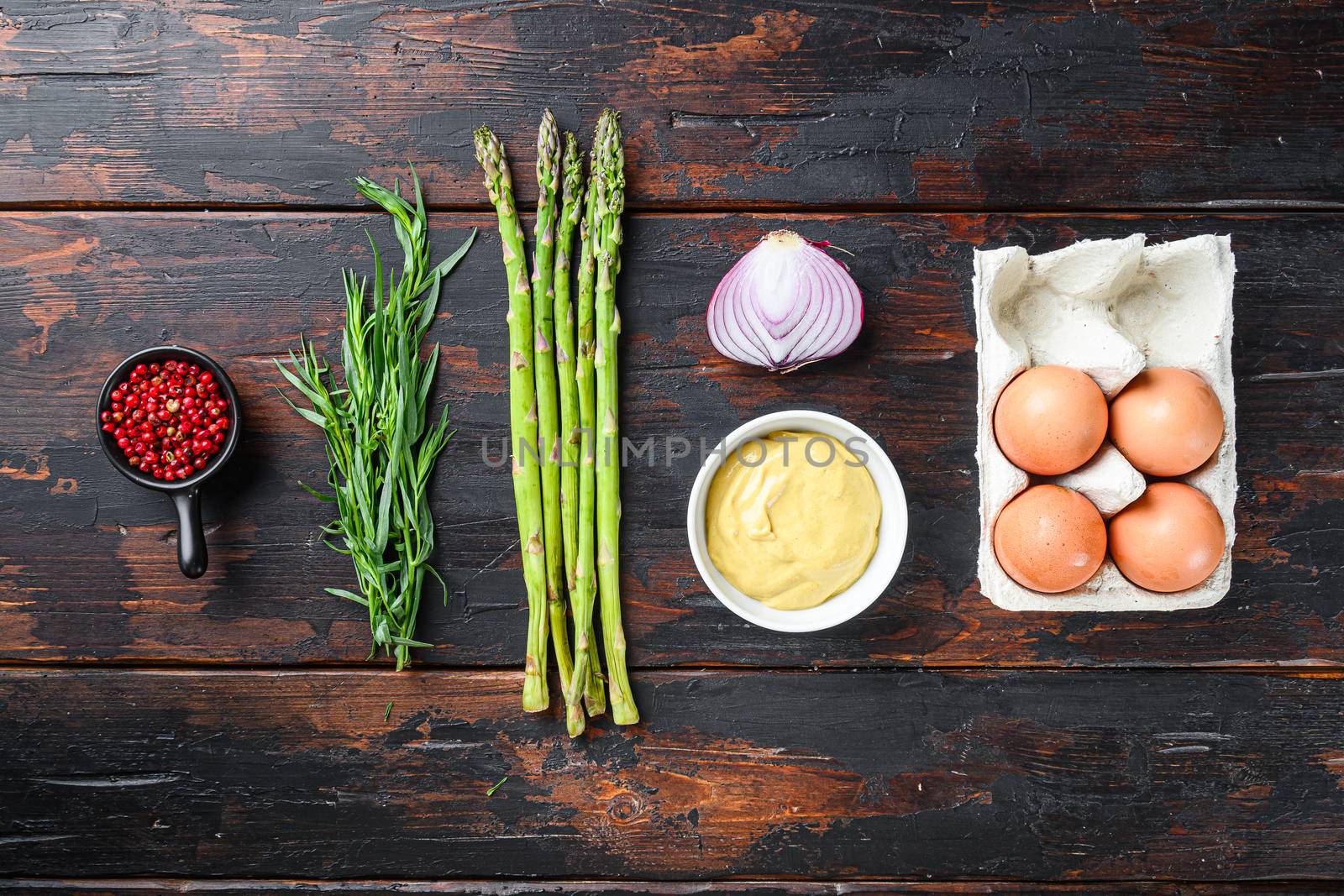 Fresh asparagus eggs and french dressing ingredients with dijon mustard, onion taragon on dark wooden old background, top view