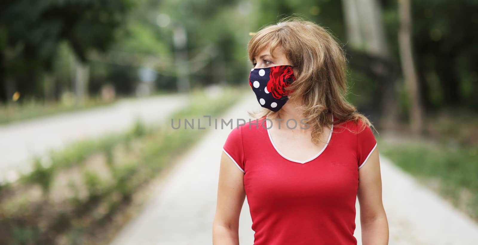 Girl in a protective mask against coronavirus in the park. Primary red color