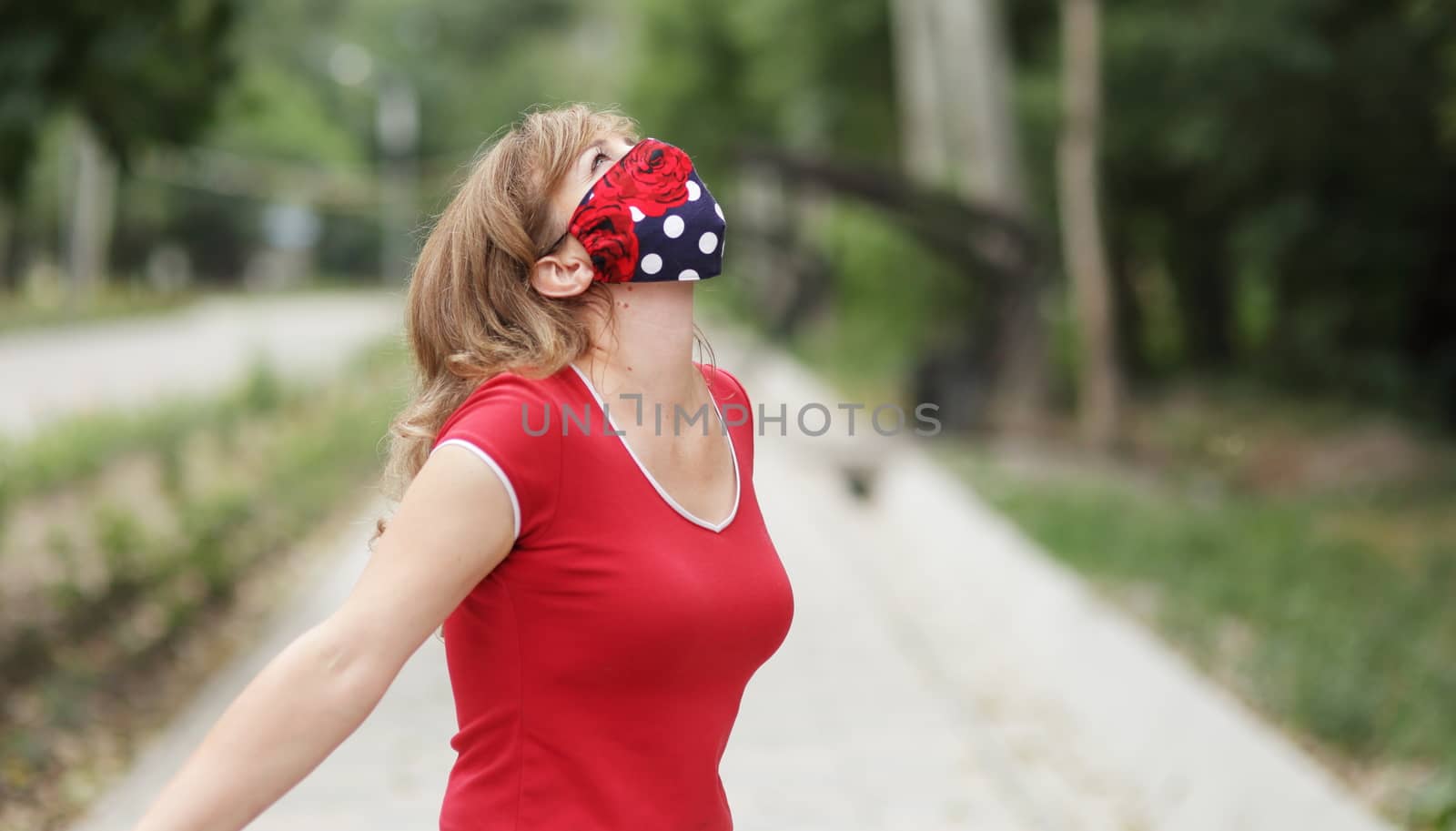 Girl in a protective mask against coronavirus in the park. by selinsmo