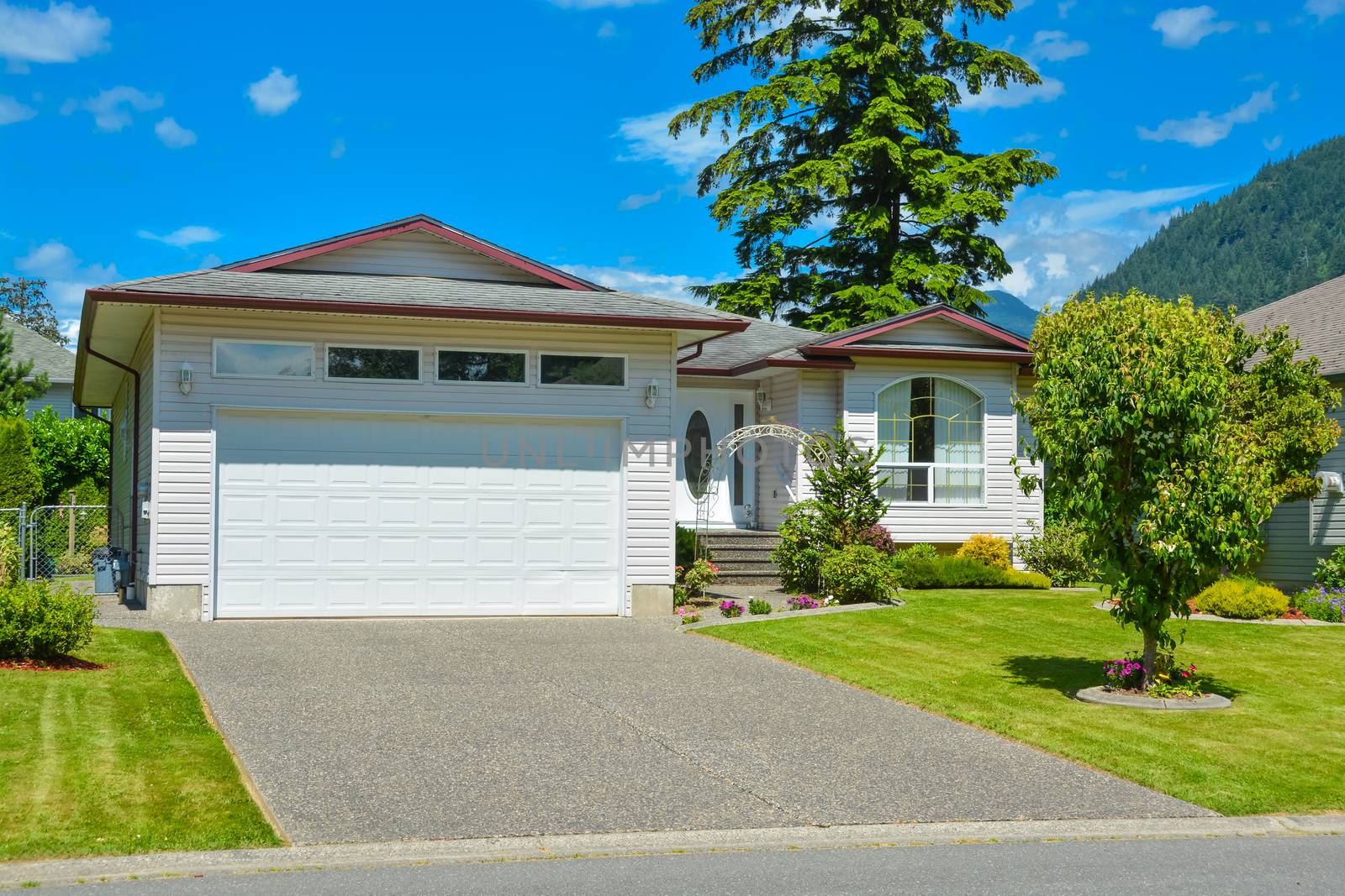 A perfect neighborhood. Nice family house with wide garage door on sunny day in British Columbia