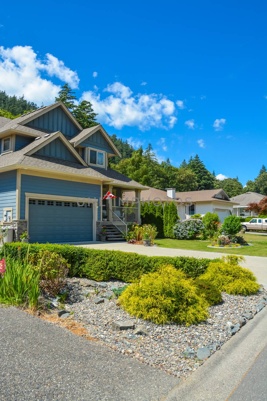 Fragment of a family house with landscaping on the front and blue sky background. House with wide garage gate