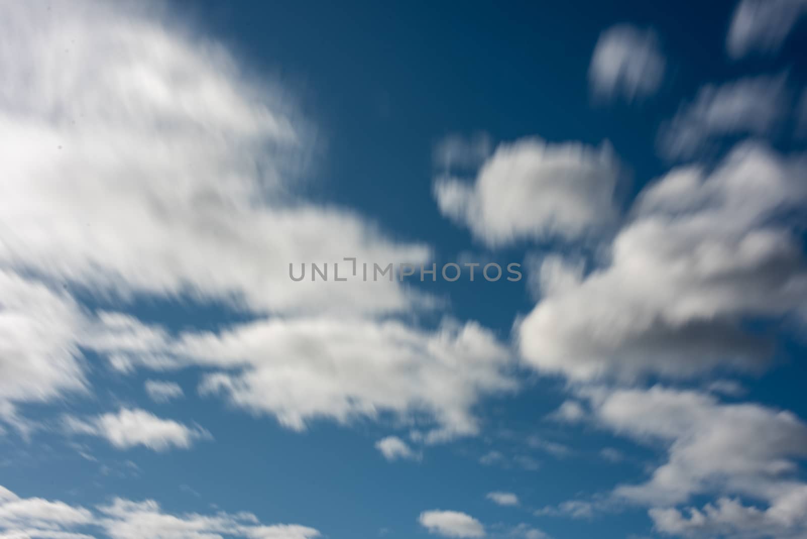 Blurred motion of moving clouds with clear blue skyline by rushay