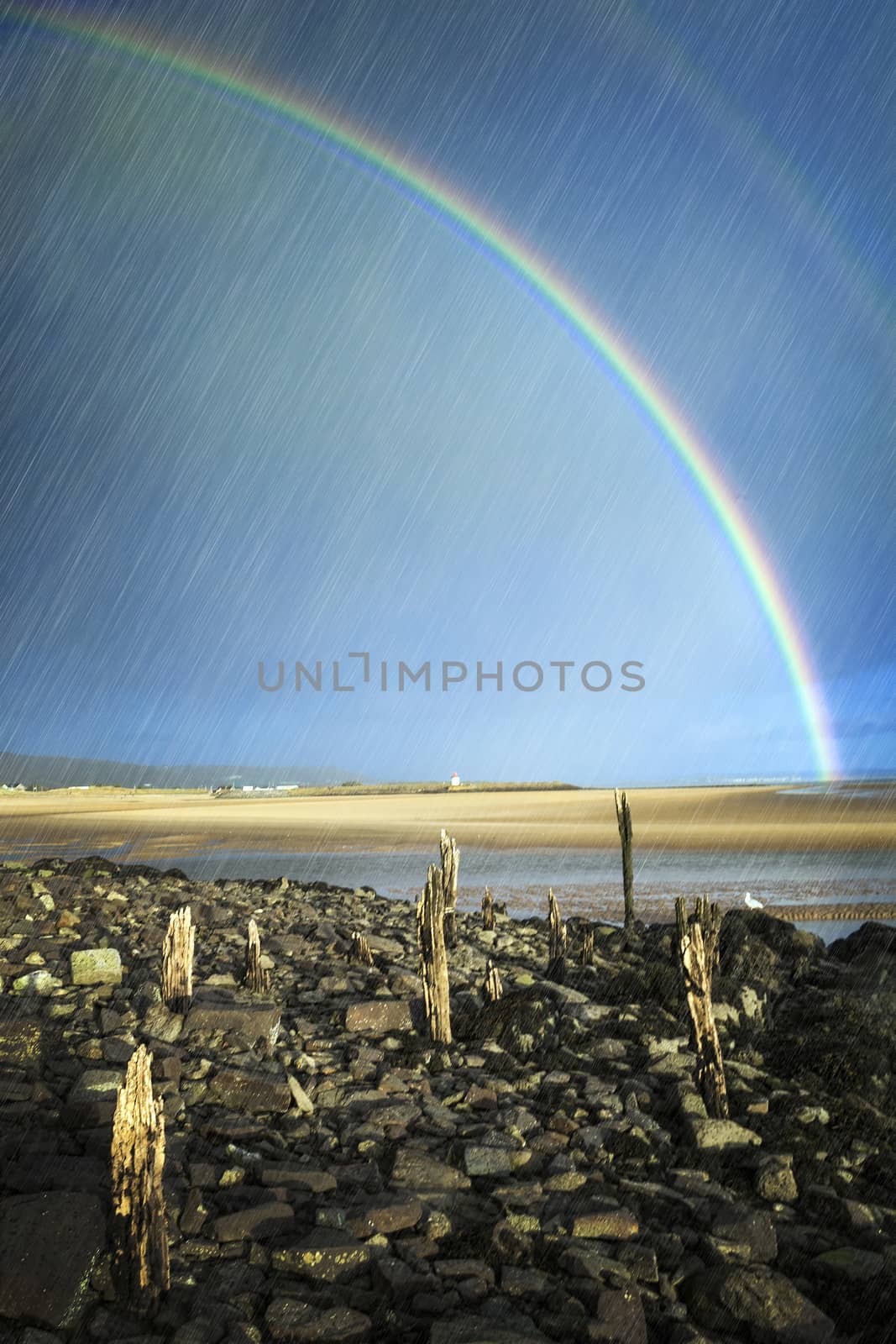 Rainbow and rain over the coastline beach at Burry Port Carmarthenshire Wales UK